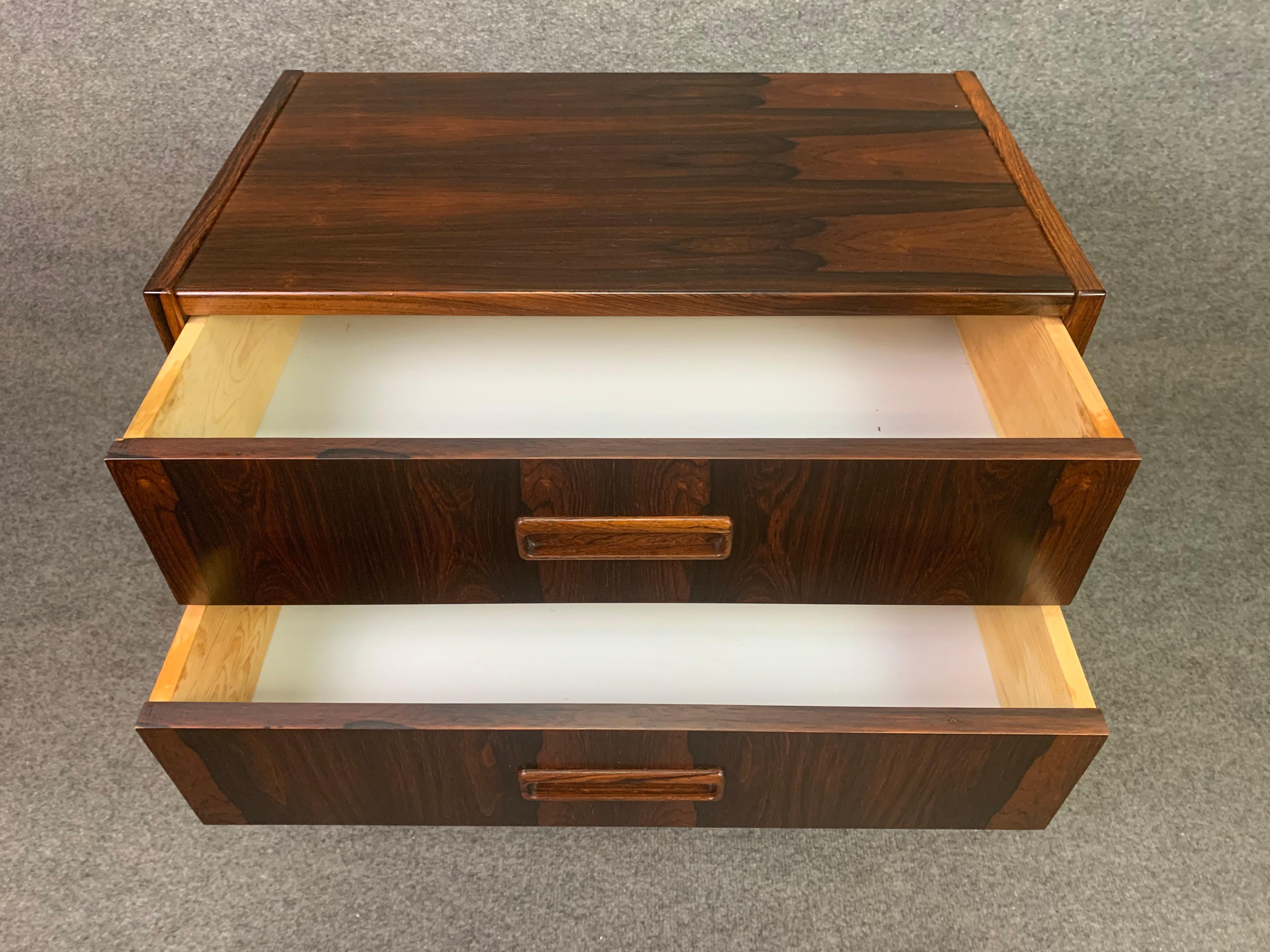 Here is a beautiful Scandinavian modern small chest in rosewood manufactured in Denmark in the 1960s.
This lovely piece features a vibrant wood grain, two dove tail built drawers with sculpted recessed pulls and four solid tapered legs.
Excellent