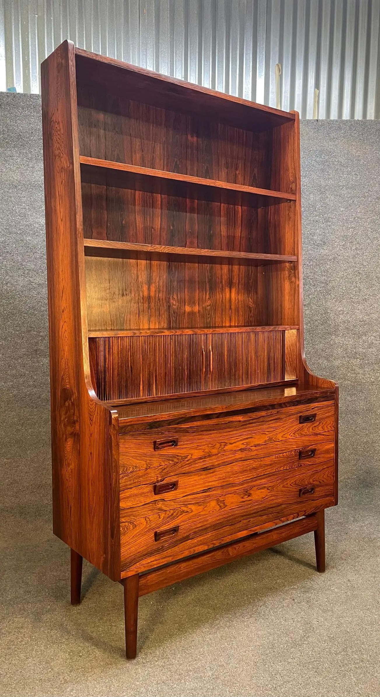 Here is a very sought after Scandinavian modern secretary desk designed by Johannes Sorth for Nexxo Mobelfabrik in Denmark in the 1960's. This exquisite piece, in Brazilian rosewood, features in the center two tambour doors with three small drawers