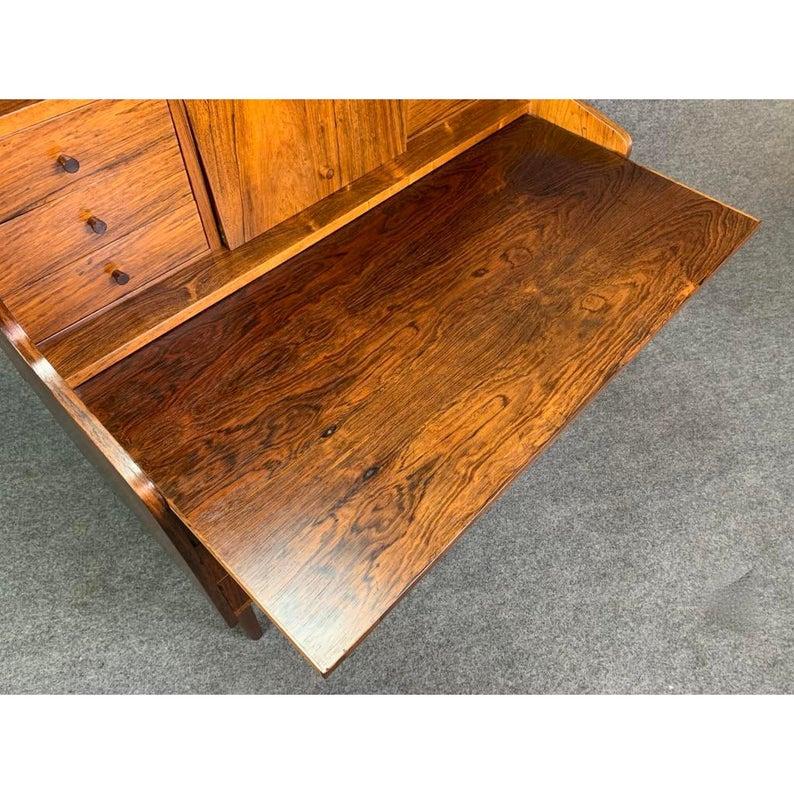 Here is a beautiful Scandinavian Modern 1960s secretary desk in rosewood recently imported from Denmark to California.
This exquisite piece, with its vibrant wood grain, offers on its upper section a horizontal storage area, two banks of three