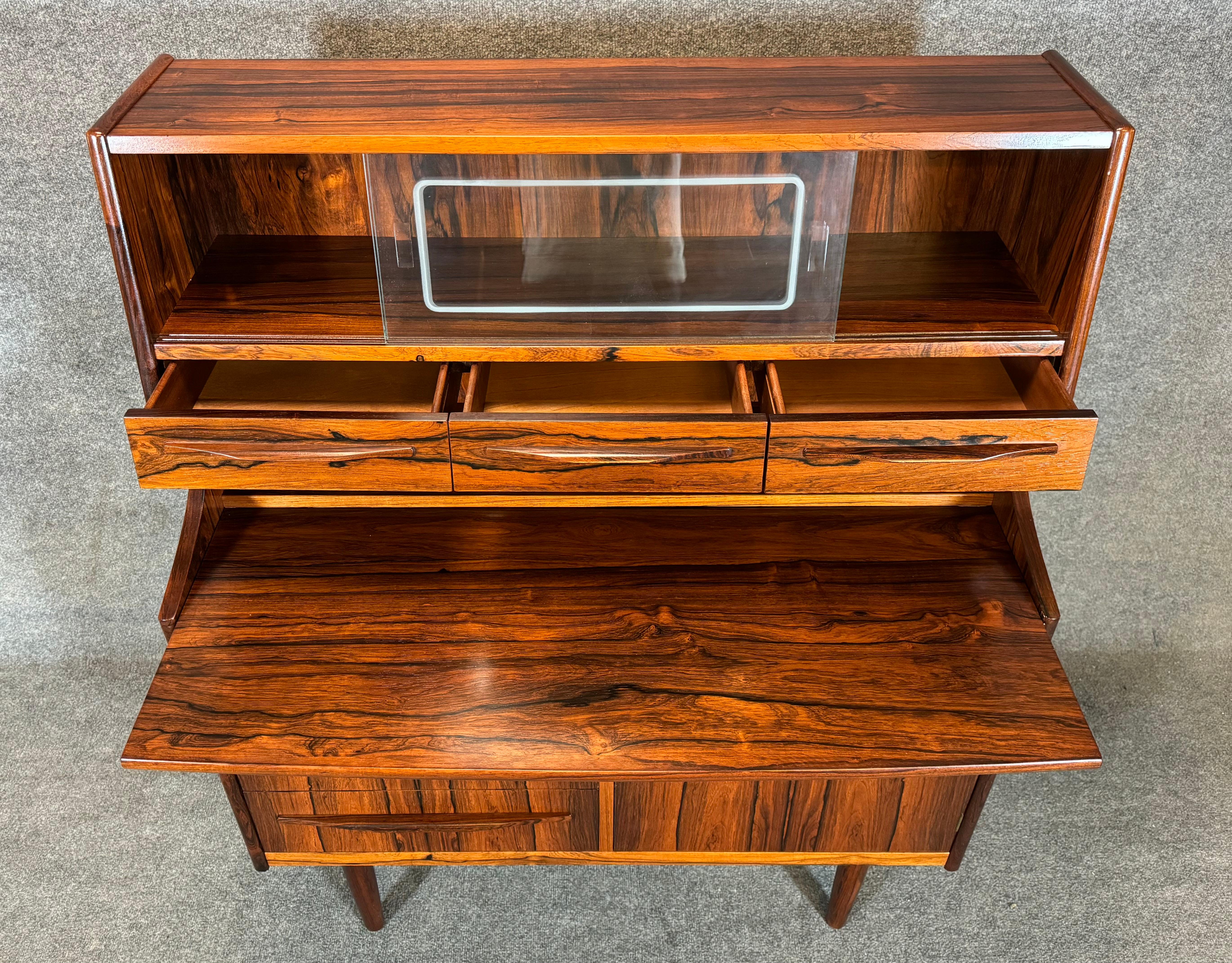 Here is a beautiful scandinavian modern secretary desk in rosewood attributed to Gunnar Falsig, Denmark, 1960's.
This exquisite piece, recently imported from Europe to California before its refinishing, features a vibrant wood grain, a slide our