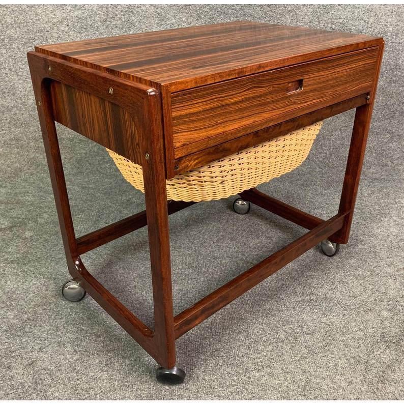 Here is a rare and versatile sewing basket in rosewood and cane manufactured by BR Gelsted in Denmark in the 1960's.
This lovely piece features a vibrant wood grain, a drawer with compartments, a slide in/out storage cane basket and a set of smooth