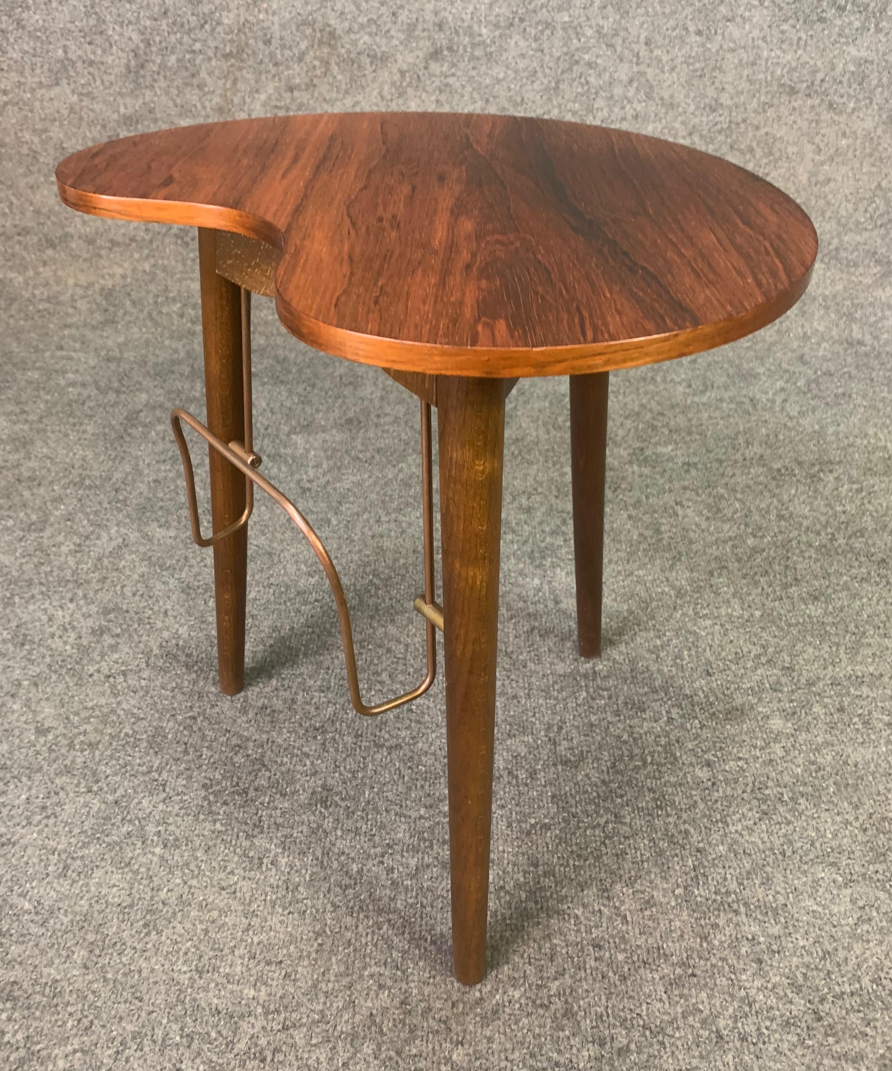 Here is a rare and special Scandinavian Modern side table in rosewood manufactured by Gorm Mobler in Denmark in the 1960s.
This table features an organic kidney shape, a top with vibrant wood grain, three solid wood tapered legs and a book