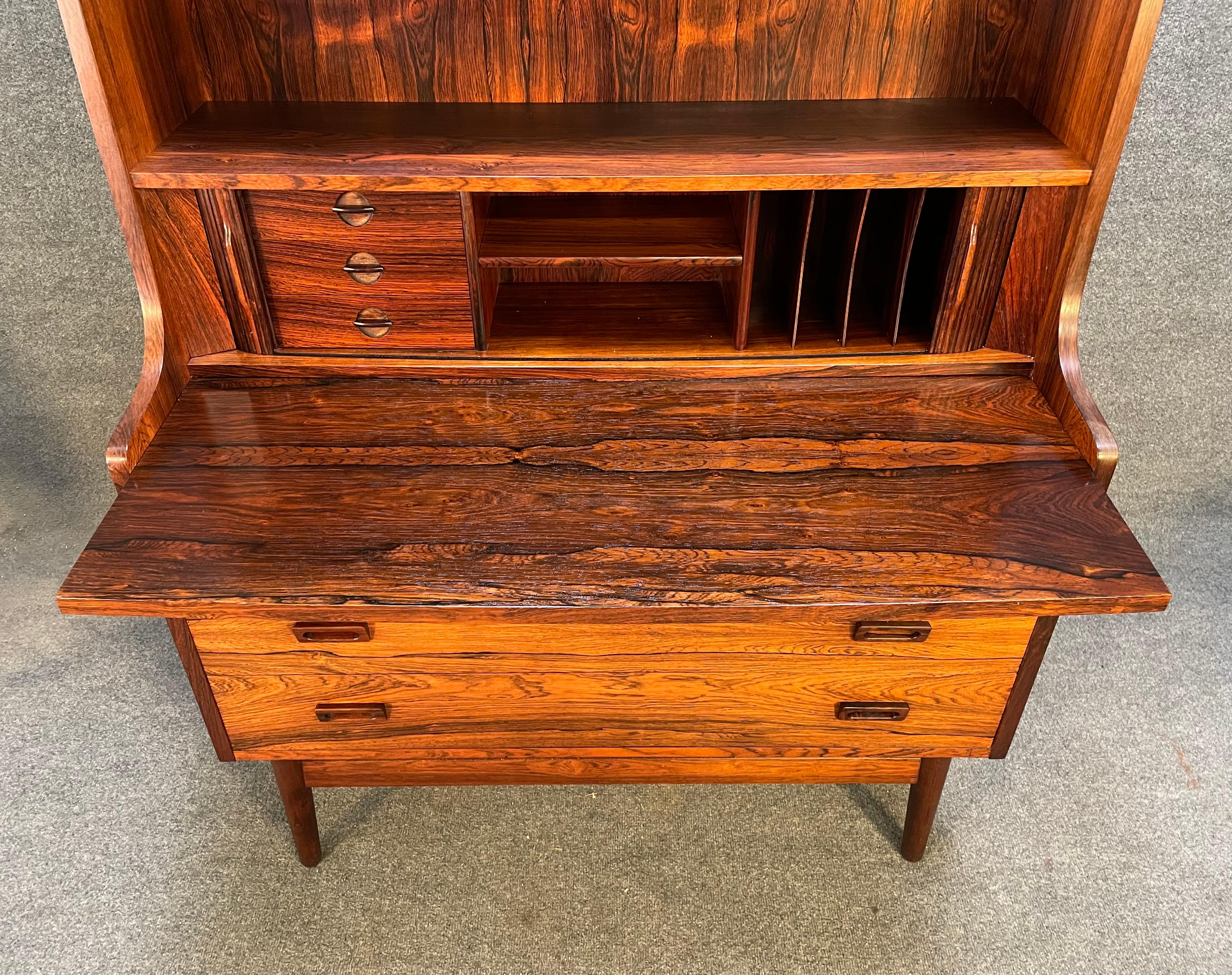 Here is a very sought after Scandinavian modern secretary desk designed by Johannes Sorth for Nexxo Mobelfabrik in Denmark in the 1960's. This exquisite piece, in Brazilian rosewood, features in the center two tambour doors with three small drawers