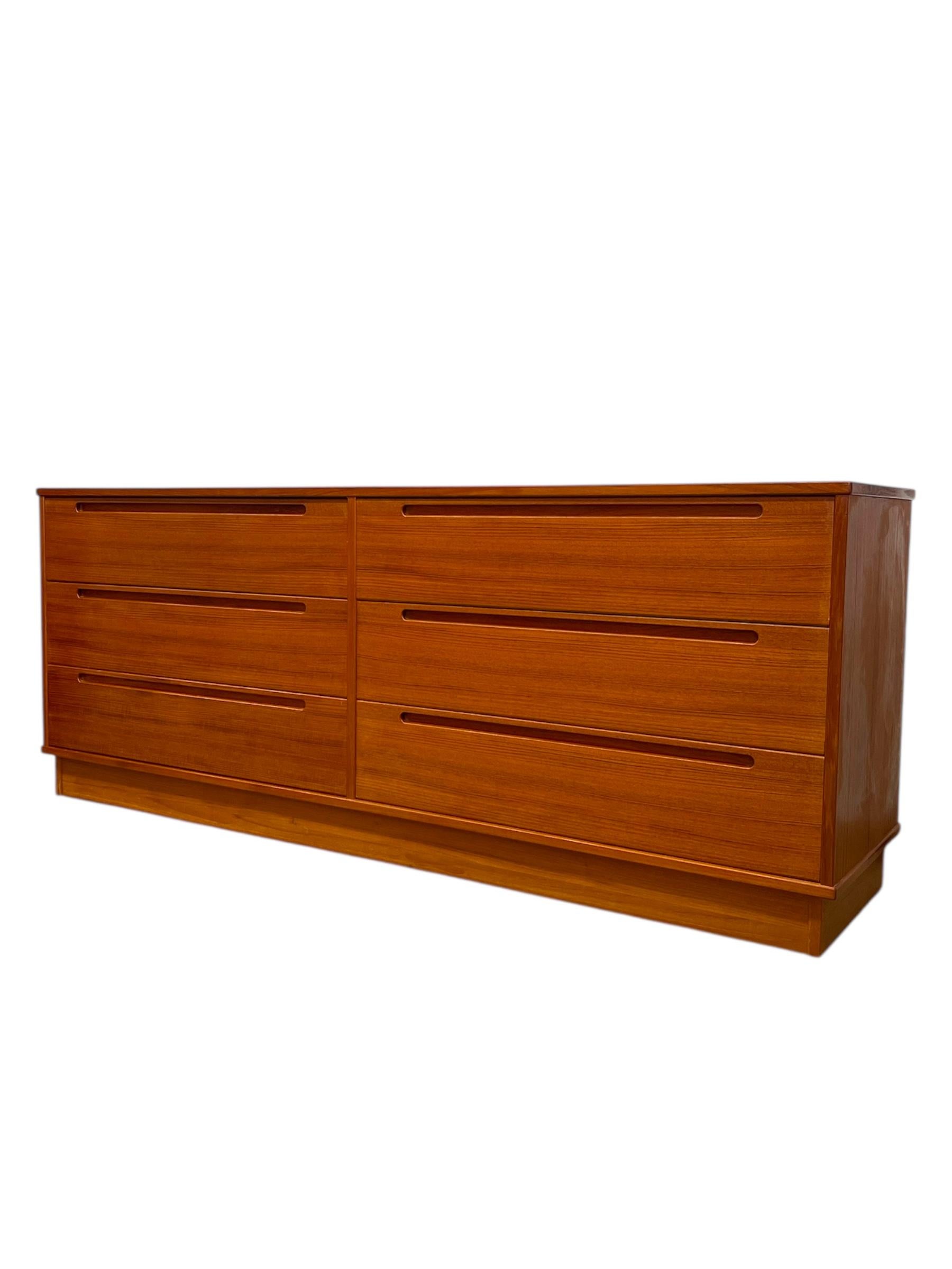 Questa cassettiera vintage danese Mid-Century Modern, disegnata da Nils Jonsson per Torring Mobelfabrik, presenta una silhouette pulita e un'eccezionale maestria tipica del design scandinavo.
Realizzato in teak con una ricca venatura, il mobile