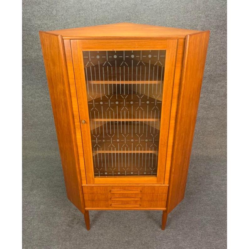 Here is a beautiful vintage corner cabinet in teak with a retro pattern etched glass recently imported from Copenhagen to San Diego.
The cabinet was manufactured in the late 1960s in Denmark and is attributed to Omann Jun.
It features a set of