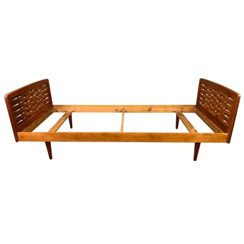 Here is a beautiful 1960s Scandinavian Modern teak bed frame recently imported from Denmark to California.
It features two solid teak head/foot board with lattice panels, a teak frame and four tapered legs in solid wood.
Fully restored and now in
