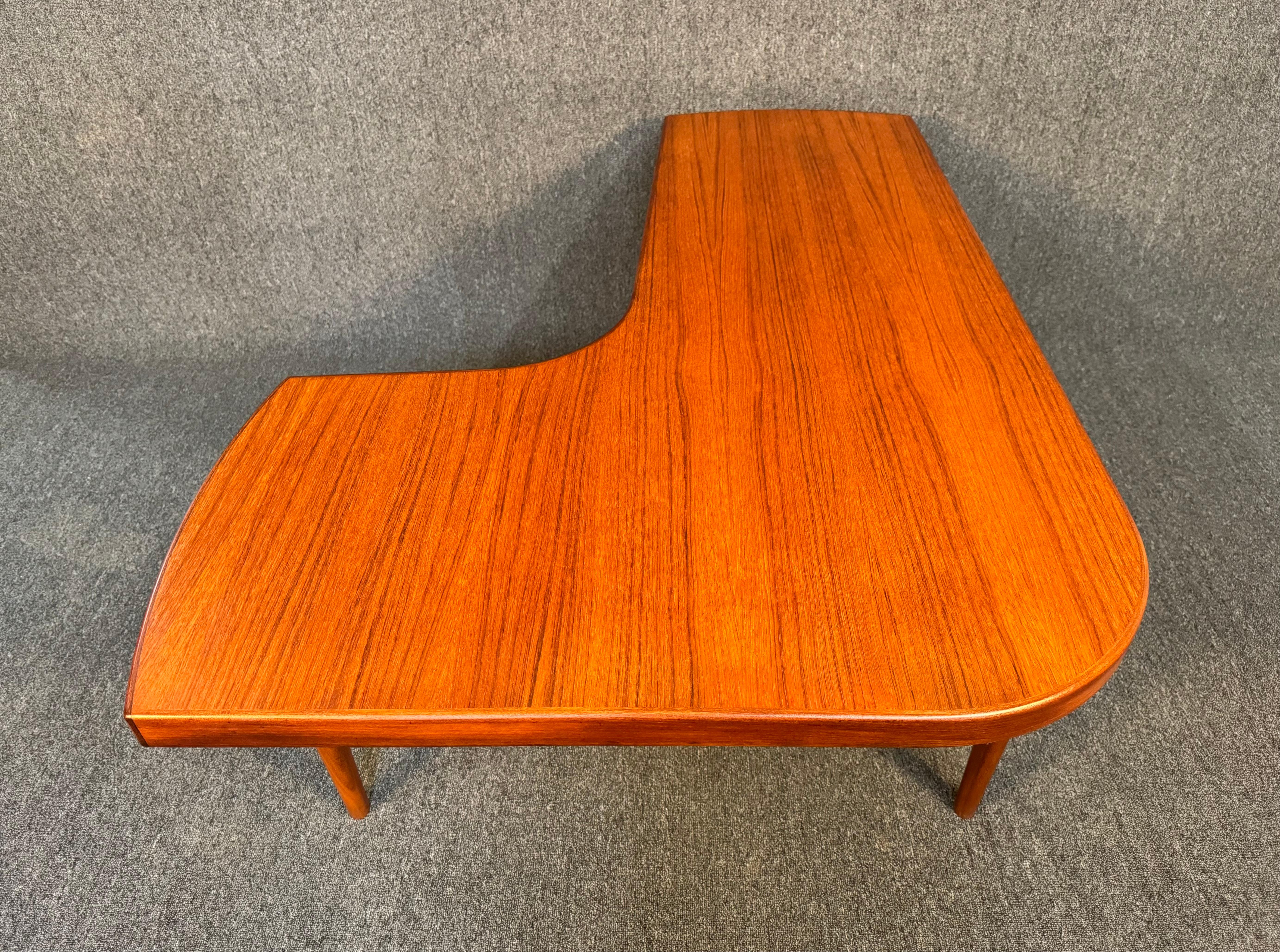 Here is a beautiful Scandinavian modern coffee table in teak wood manufactured in Denmark in the 1960's.
This lovely table, recently imported from Europe to California before its refinishing, features a vibrant wood grain, a boomerang - L shaped top