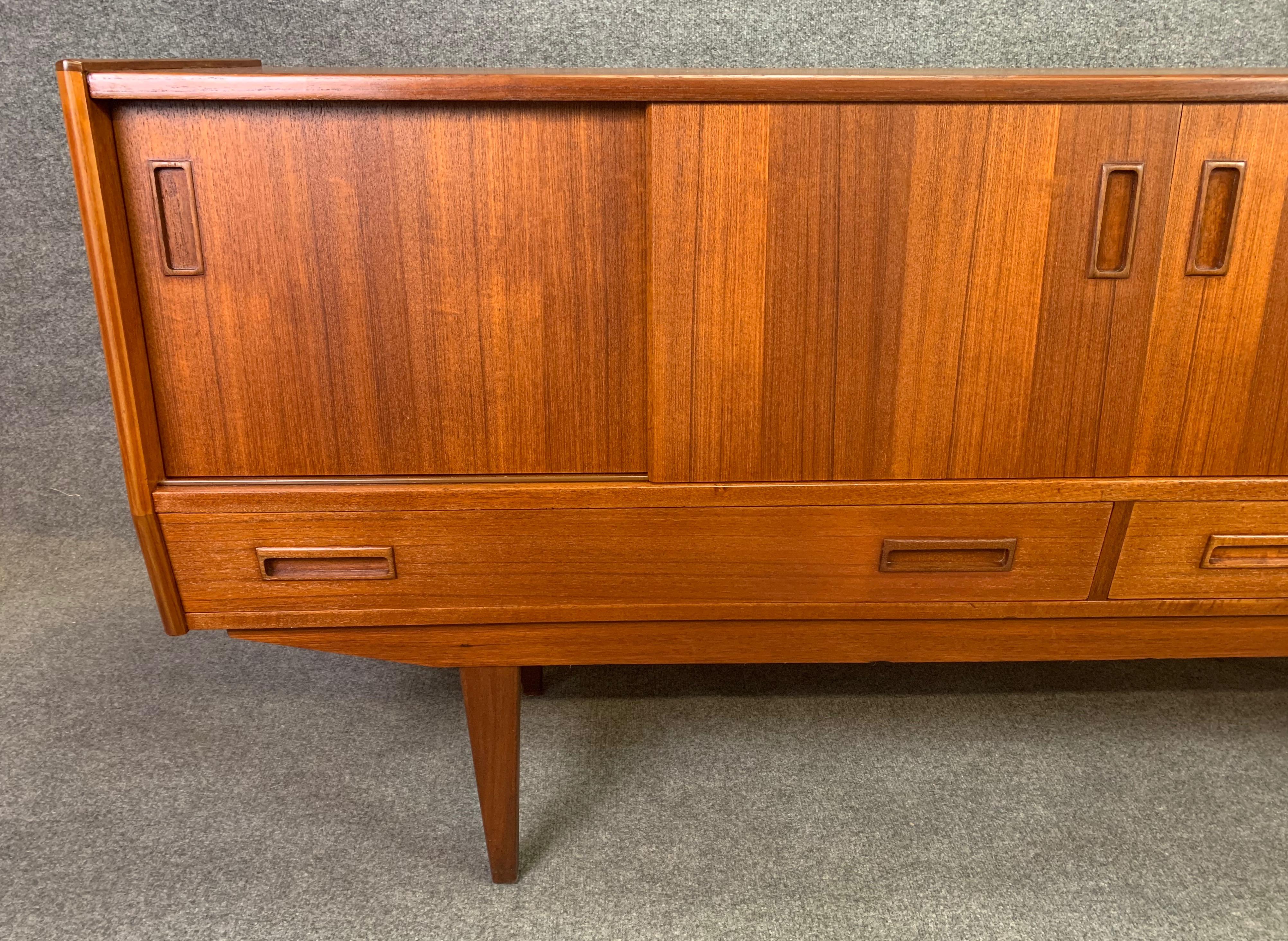 Here is a beautiful 1960s Scandinavian Modern teak sideboard recently imported from Denmark to California before its restoration.
This exquisite credenza features a vibrant wood grain, four sliding doors revealing storage cubbies with adjustable