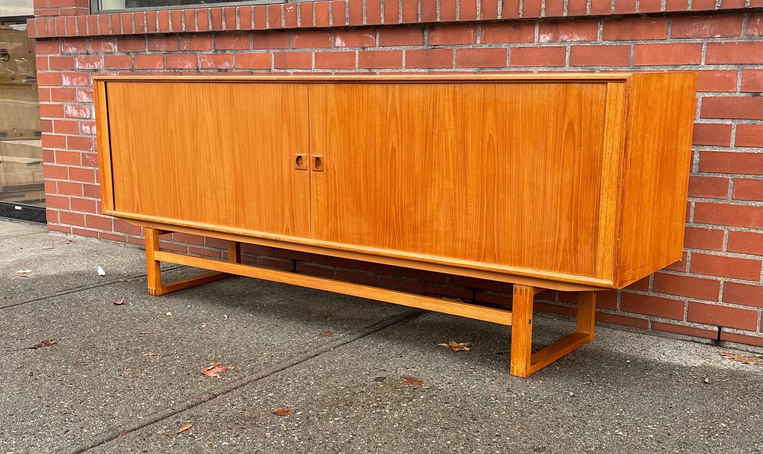 Wonderful Danish design sideboard from the 1950s. The sideboard is made from teak and has beautiful tambour doors who disappear completely when opened. Characteristic for this sideboard is the square base that gives the sideboard a very clean and