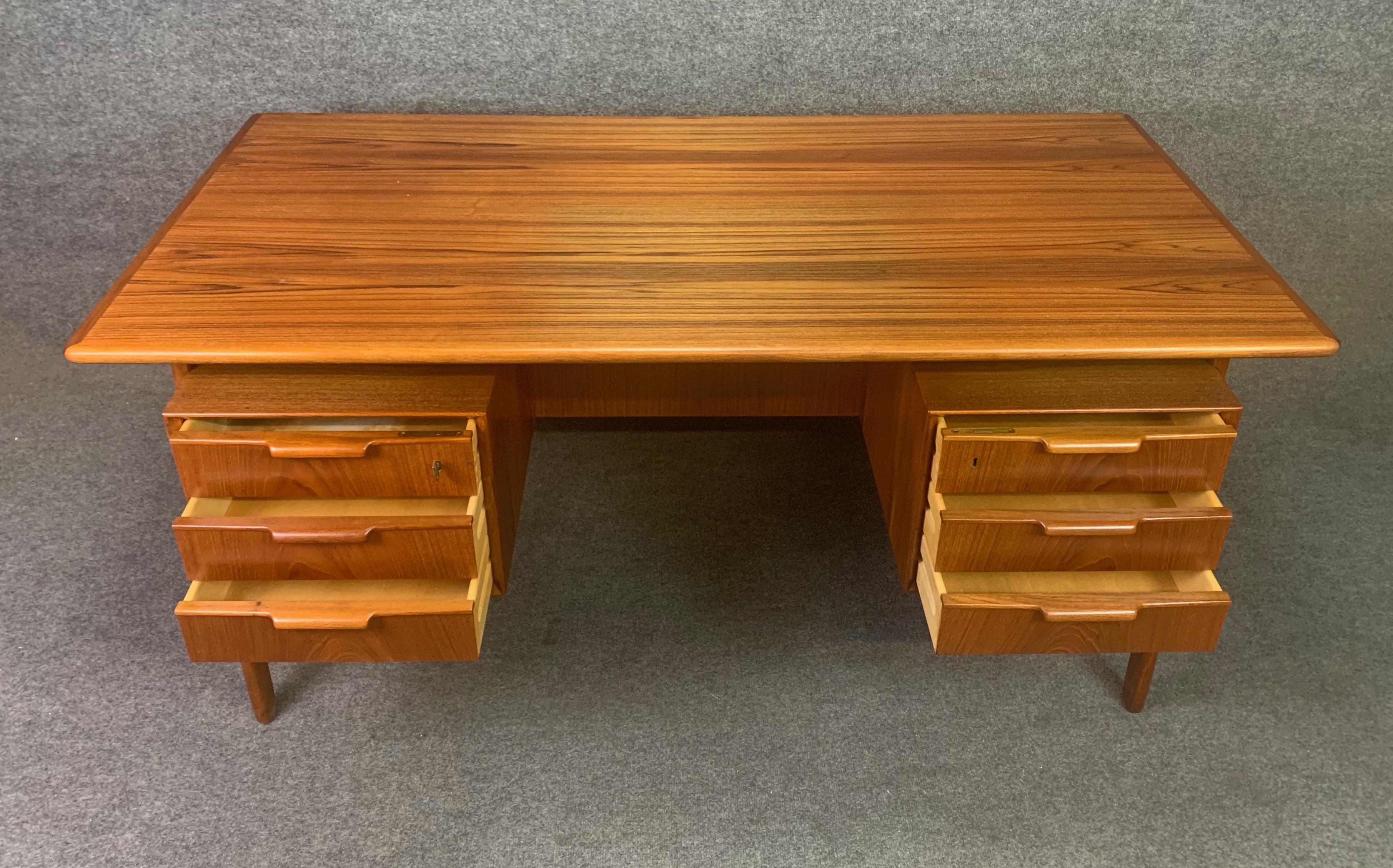 Here is the iconic Model 75 desk in teak designed by Gunni Omann and manufactured by Omann Jun Mobelfabrik which was recently imported from Denmark to California before its restoration. This stunning 1960s Scandinavian Modern teak desk features a