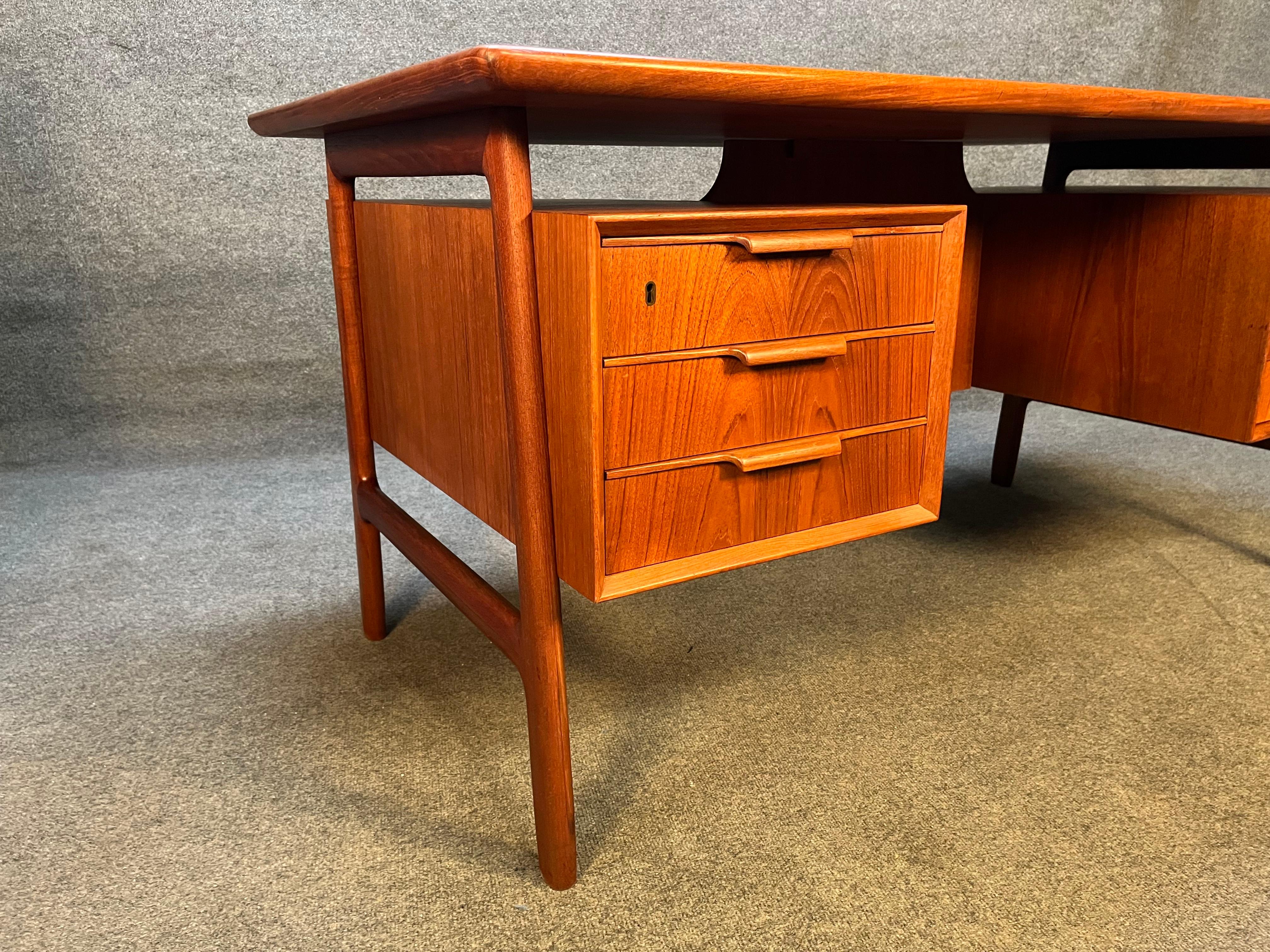 Here is the iconic Model 75 desk designed by Gunni Omann and manufactured by Omann Jun Mobelfabrik. This stunning 1960's Scandinavian modern desk in teak wood features a sculpted frame-legs supporting seamlessly two floating banks of drawer on the
