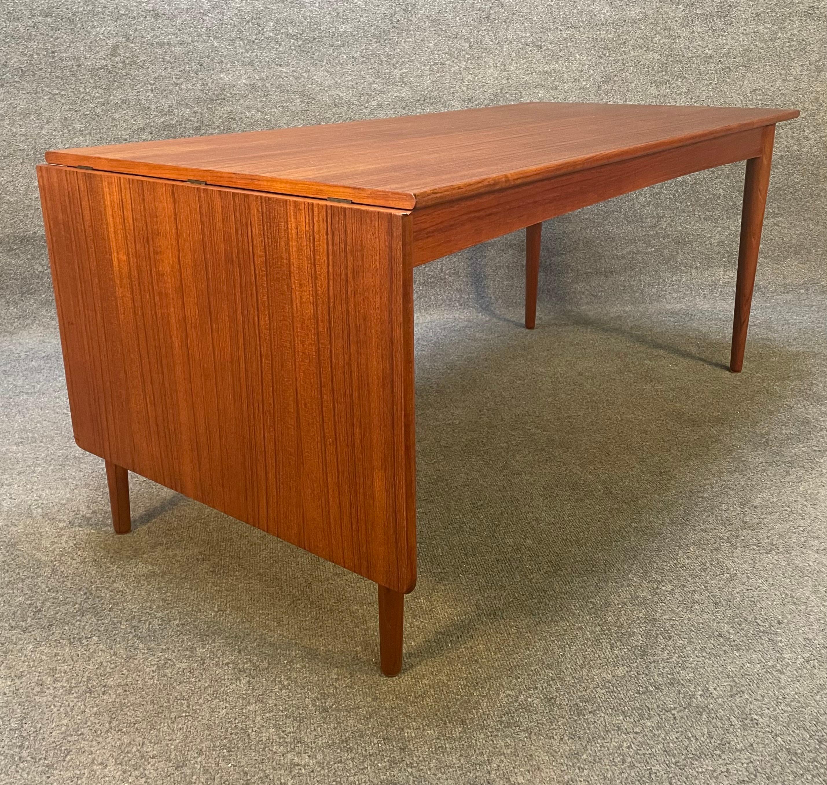 Here is a beautiful 1960's scandinavian modern coffee table in teak wood recently imported from Denmark to California before its refinishing.
This exquisite cocktail table features a vibrant wood grain, a drop leaf and four tapered legs in solid