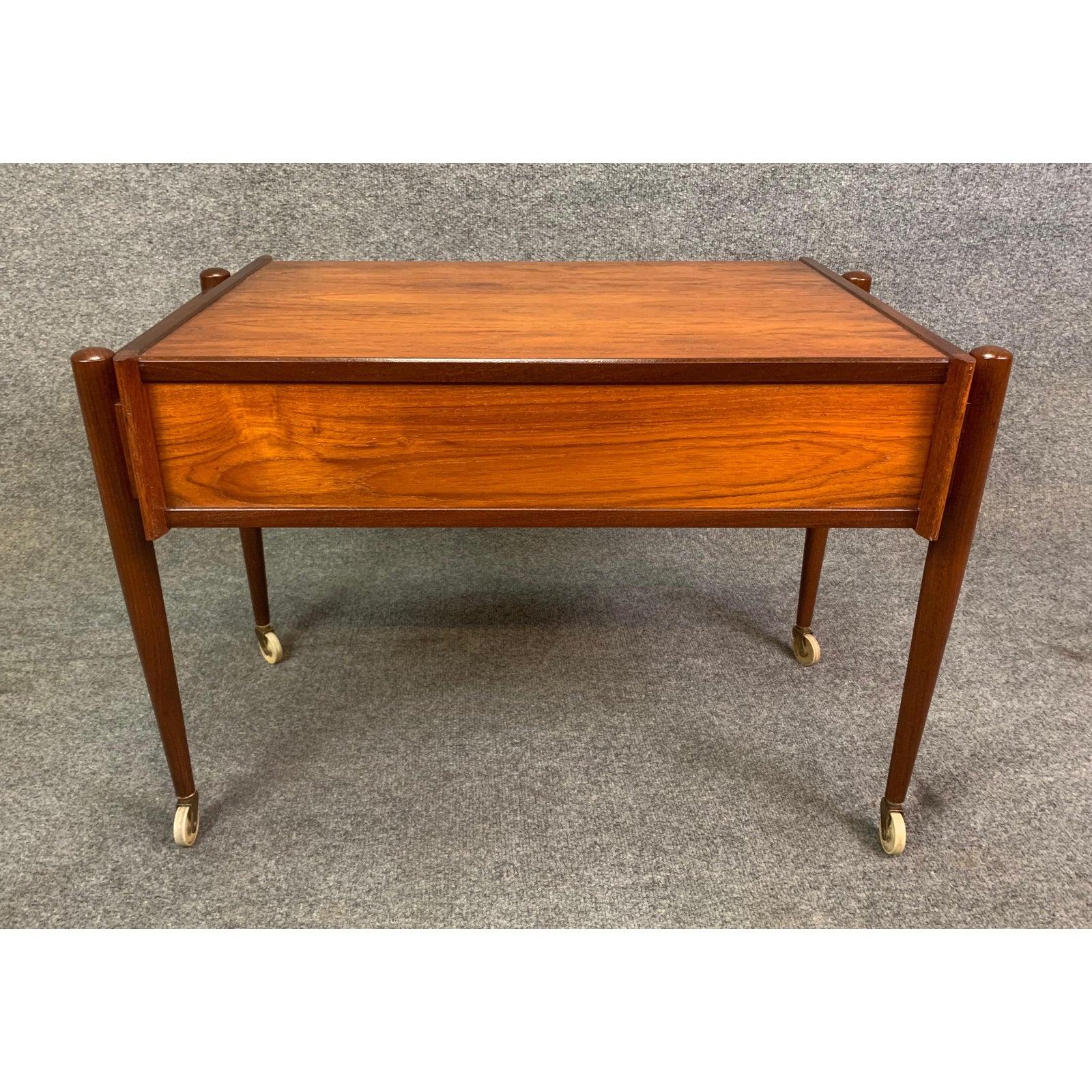 Here is a beautiful Scandinavian Modern teak nightstand - end table recently imported from Copenhagen to California before its refinishing. This exquisite piece features a vibrant wood grain, four solid afromasia wood tapered legs with casters