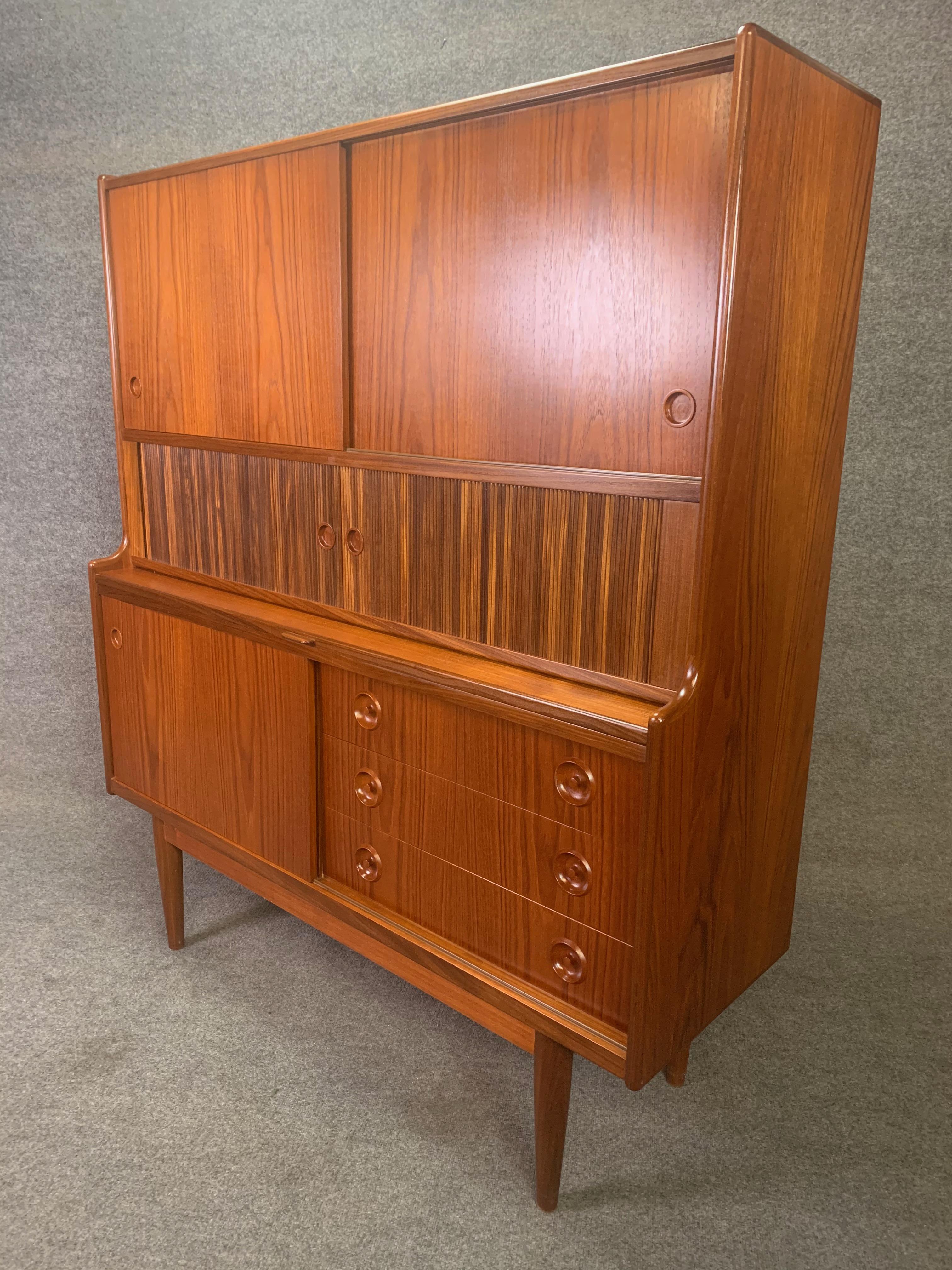 Here is a beautiful Scandinavian Modern teak high credenza designed by Johannes Andersen and manufactured by J. Skaaning Mobler in Denmark in the 1960s.
This special case piece, recently imported from Copenhagen to California, features a vibrant