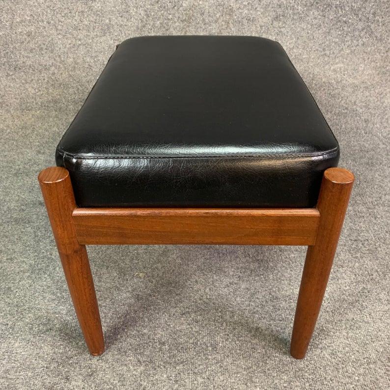 Here is an elegant vintage Scandinavian Modern foot stool in teak and black vinyl recently imported from Denmark to California.
This ottoman features a solid afromasia teak frame and a black vinyl foot rest.
Excellent vintage original