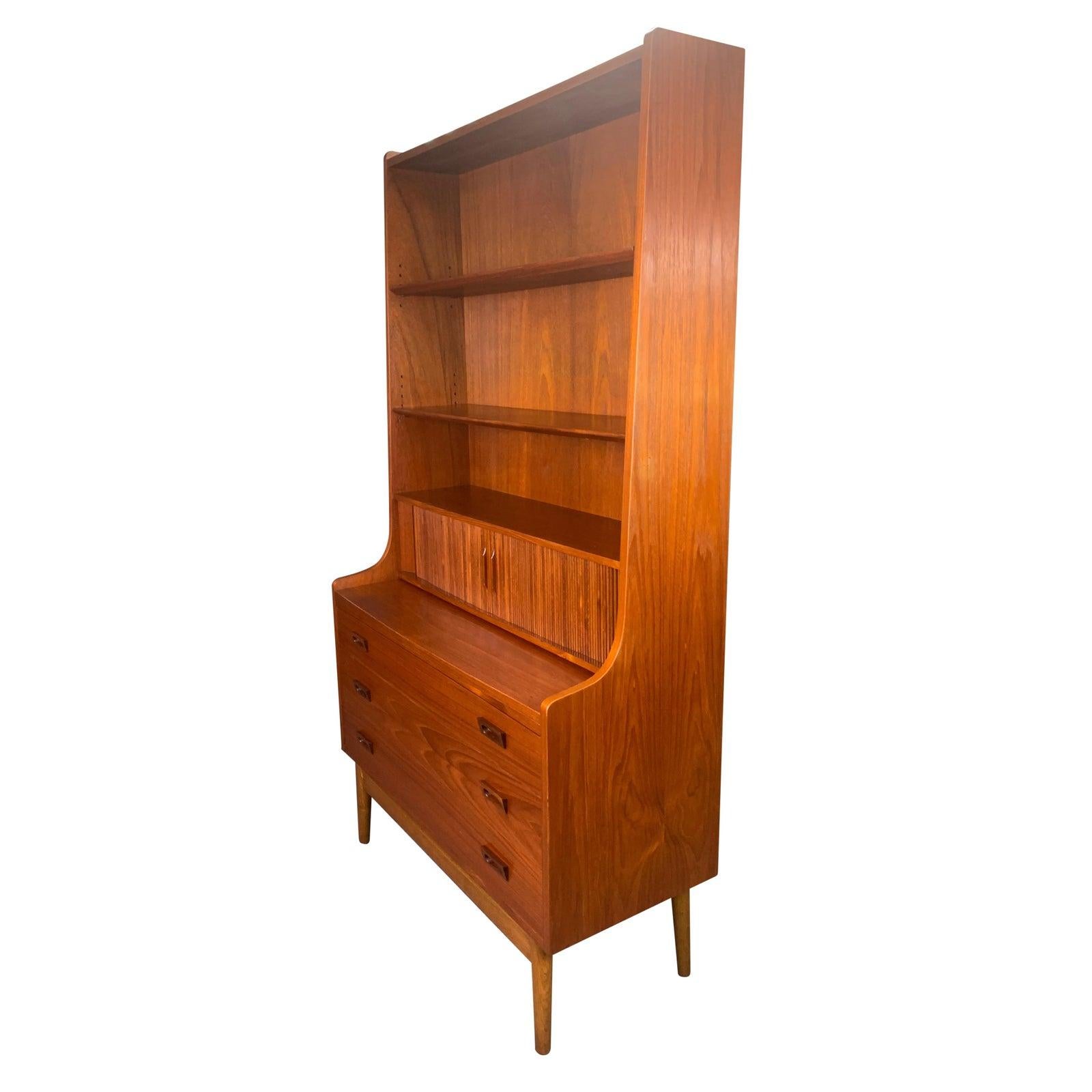 Here is a very sought after Scandinavian Modern teak secretary desk designed by Johannes Sorth for Bornholm Møbelfabrik in Nexø, Denmark in the 1960s. This exquisite piece features in the centre two tambour doors with three small drawers behind them