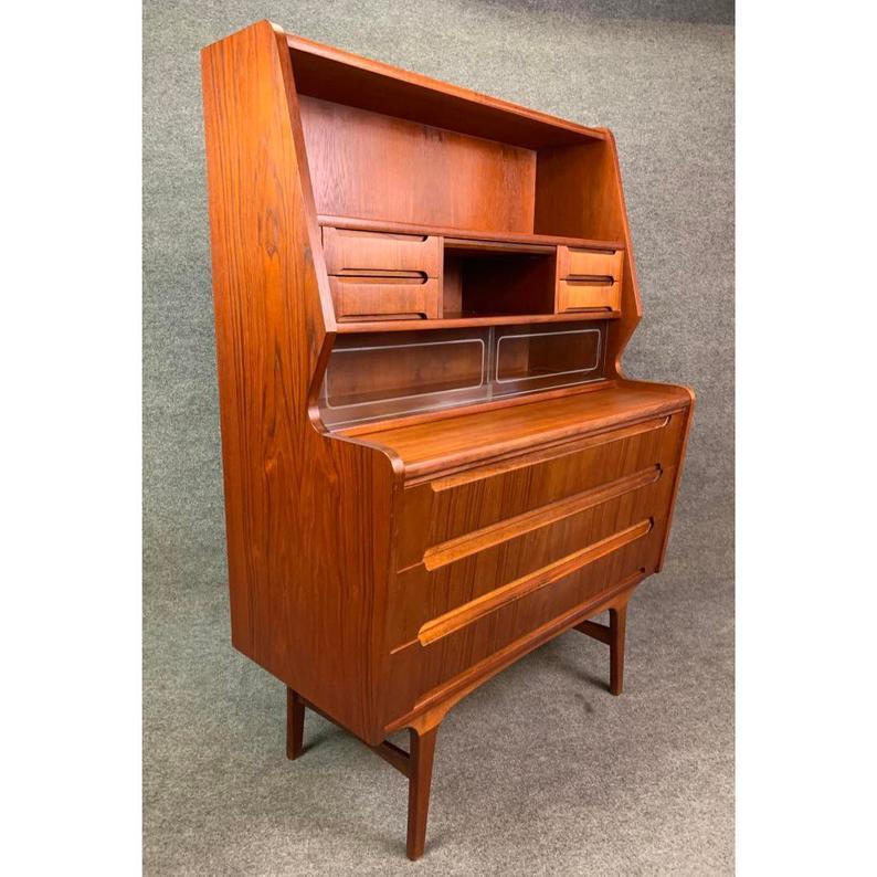 Here is a versatile 1960s Scandinavian Modern teak secretary desk recently imported from Sweden to California before its restoration. This exquisite storage piece, with its vibrant teak wood grain, has a lot to offer:
On its upper part: A set of