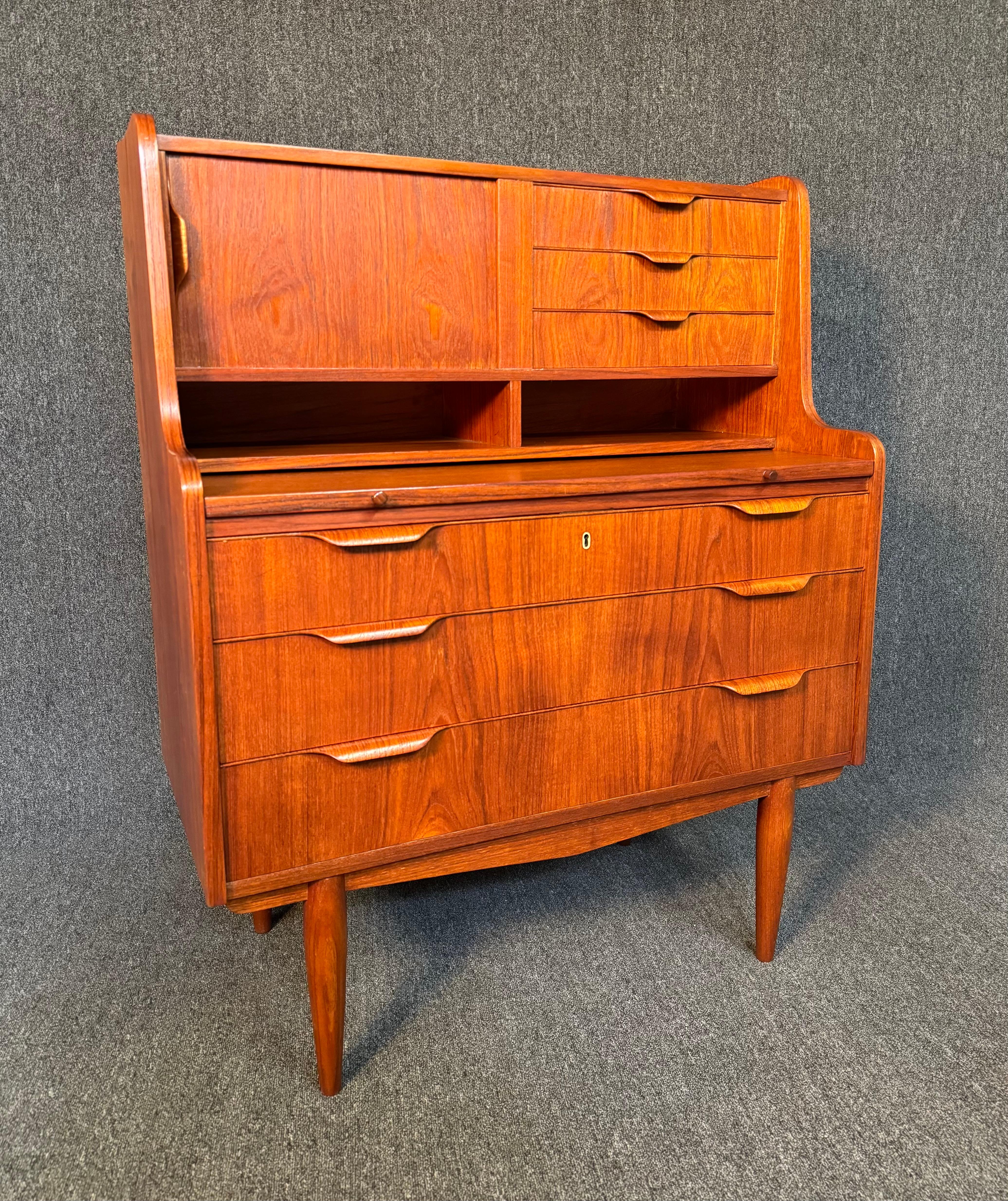 Here is a beautiful Scandinavian modern secretary desk in teak wood manufactured in Denmark in the 1960's.
This exquisite piece, recently imported from Europe to California before its refinishing, features a vibrant wood grain, multiple storage