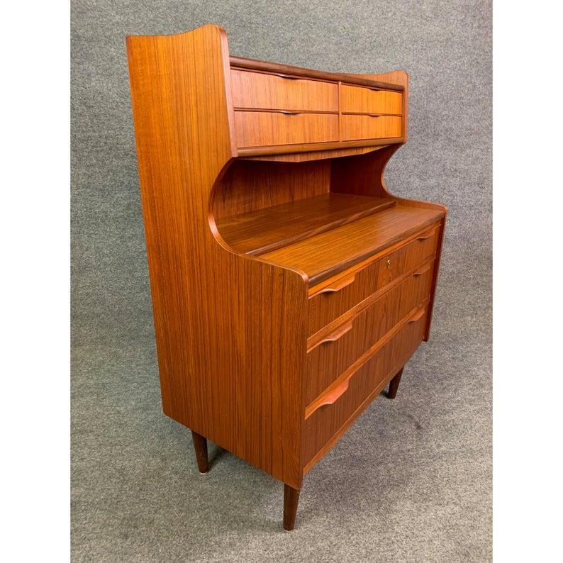 Here is a beautiful 1960s Scandinavian Modern secretary desk in teak recently imported from Denmark to California.
This lovely piece features a vibrant wood grain, four small drawers, a mirror and a slide out desk on its top and three large drawers