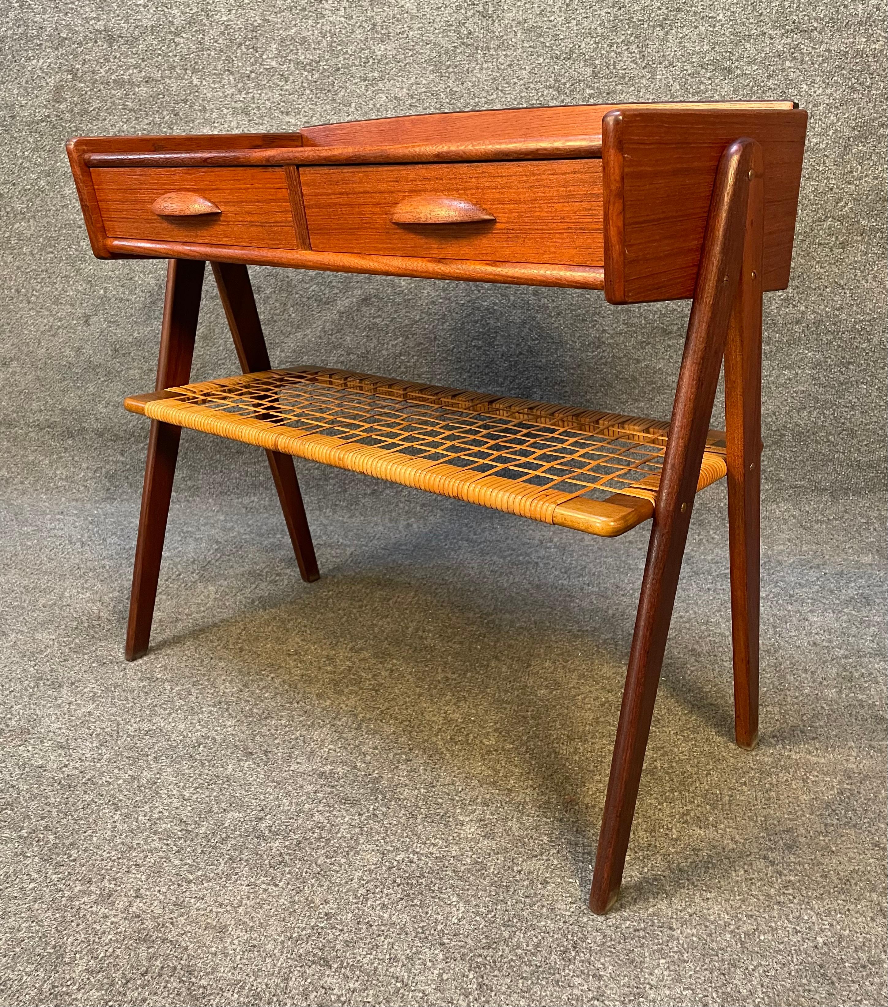 Here is a beautiful 1960's end table in teak designed by Soren Rasmussen.
This sculptural side table, fully refinished after its importation from Denmark to California, features a vibrant wood grain, two dove tail built drawers, a cane shelf and