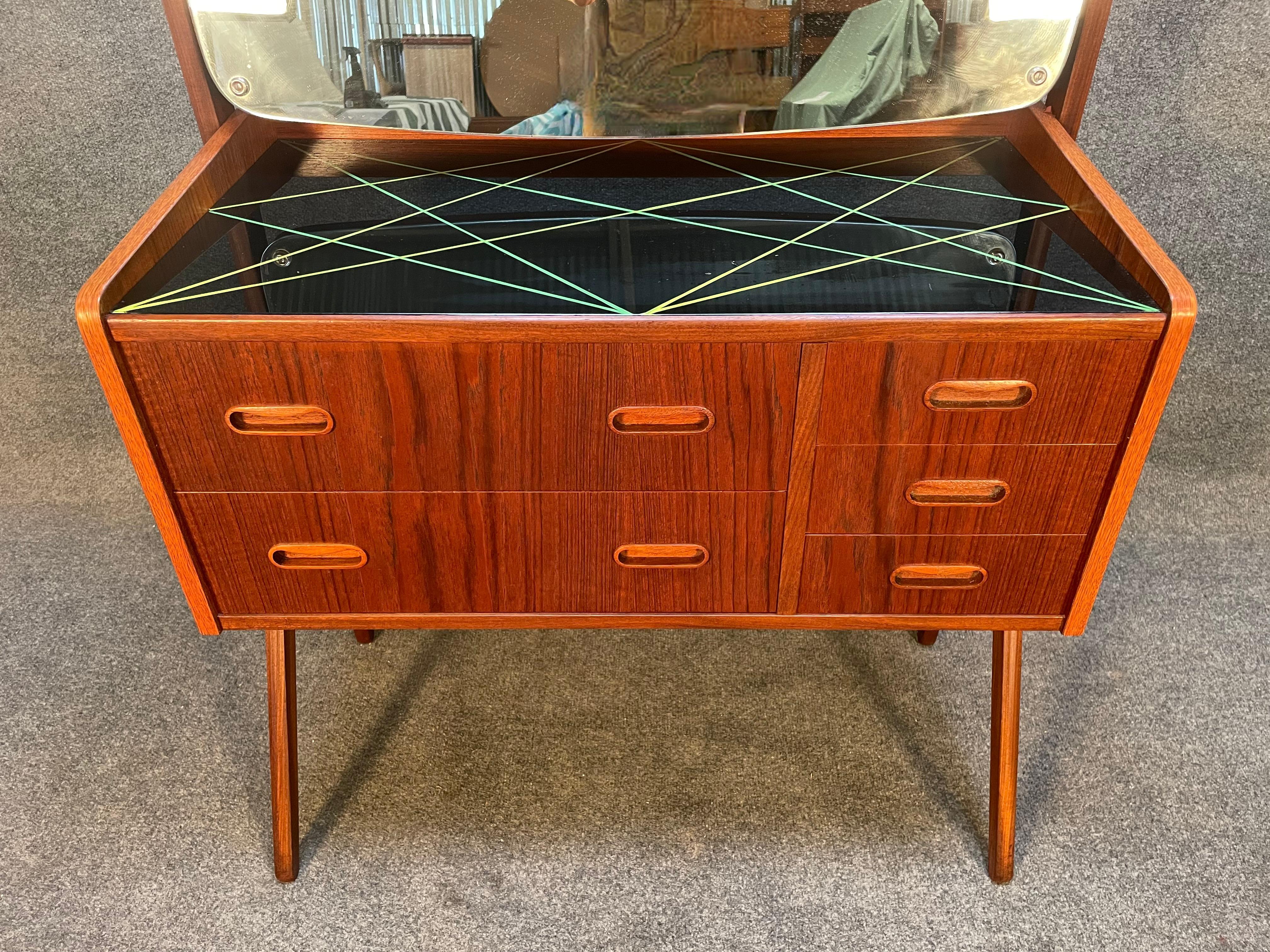 Here is a beautiful Scandinavian modern teak dressing table manufactured by Vinde Mobelfabrik in Denmark in the 1960's recently imported from Europe to California before its refinishing.
This lovely piece features 2 large drawers + 3 small drawers