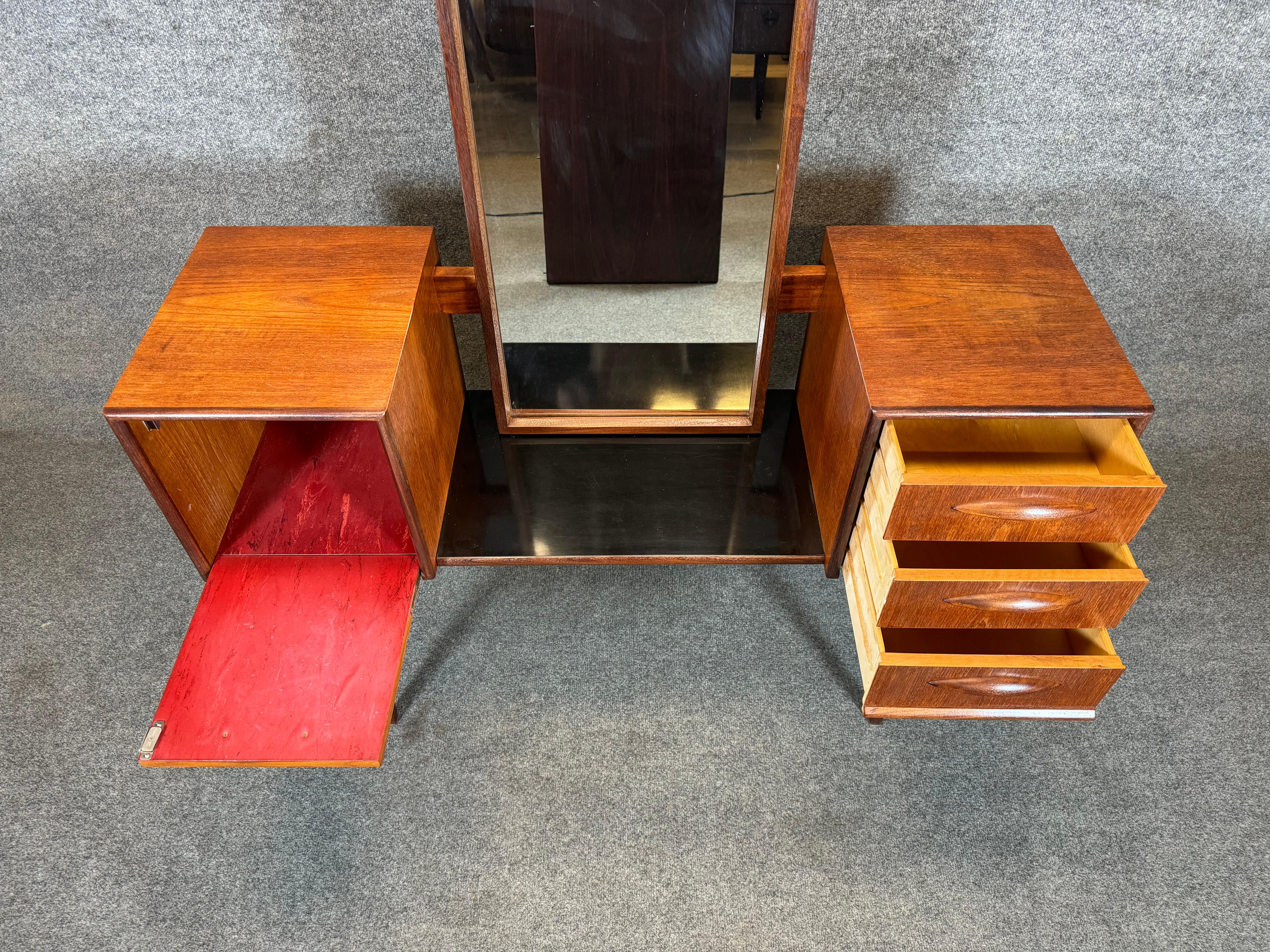 Here is a rare Scandinavian modern vanity in teak with its mirror manufactured in Denmark in the 1960's.
This lovely piece, recently imported from Europe to California before its refinishing, features vibrant wood grain, a long teak framed mirror, a