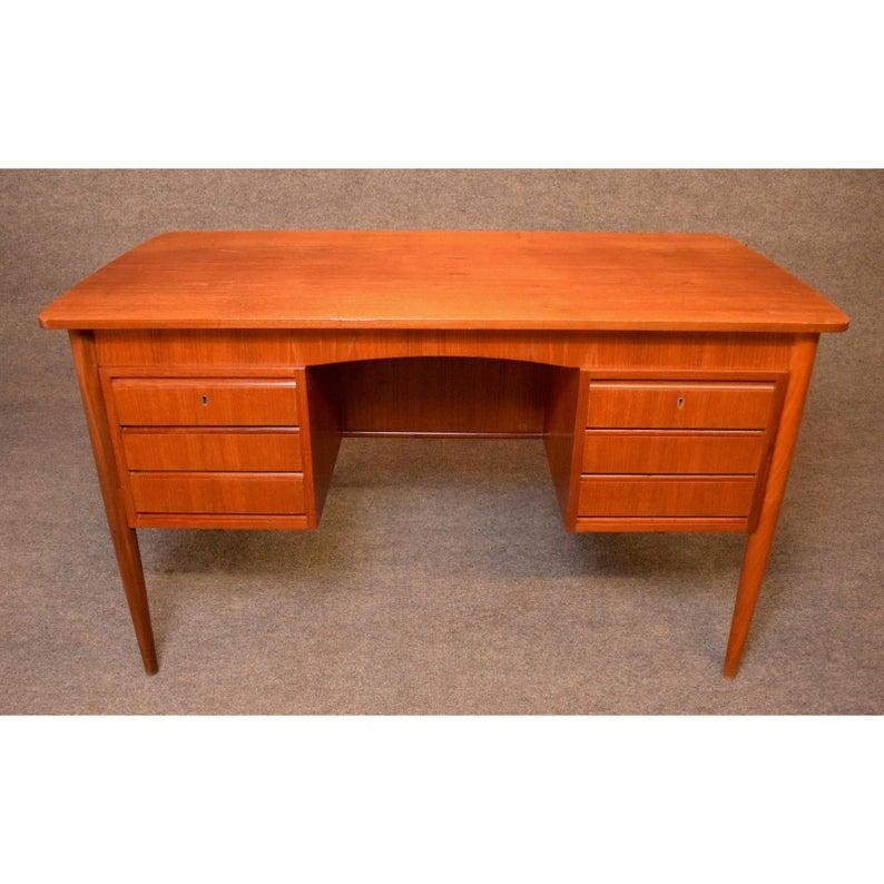 Here is a beautiful 1960s Scandinavian Modern writing desk in teak wood recently imported from Denmark to California before its restoration.
This elegant desk features a vibrant wood grain, two banks of three drawers on its front and three