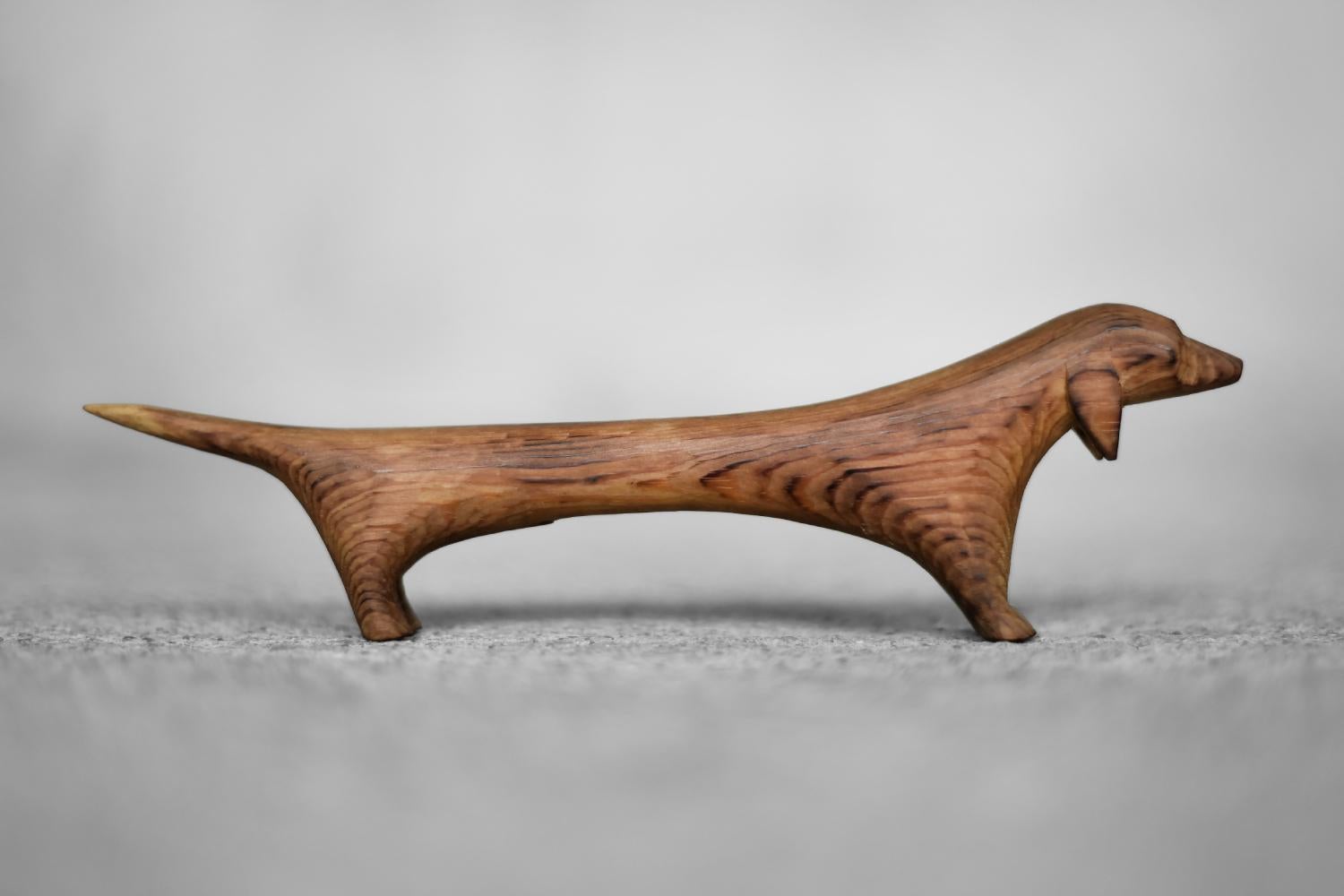 Questa statuetta di bassotto in legno è stata prodotta in Danimarca negli anni Sessanta. Realizzato a mano da un unico pezzo di legno, con una spazzolatura distinta che mette in risalto la struttura naturale del legno e le forti venature. La forma