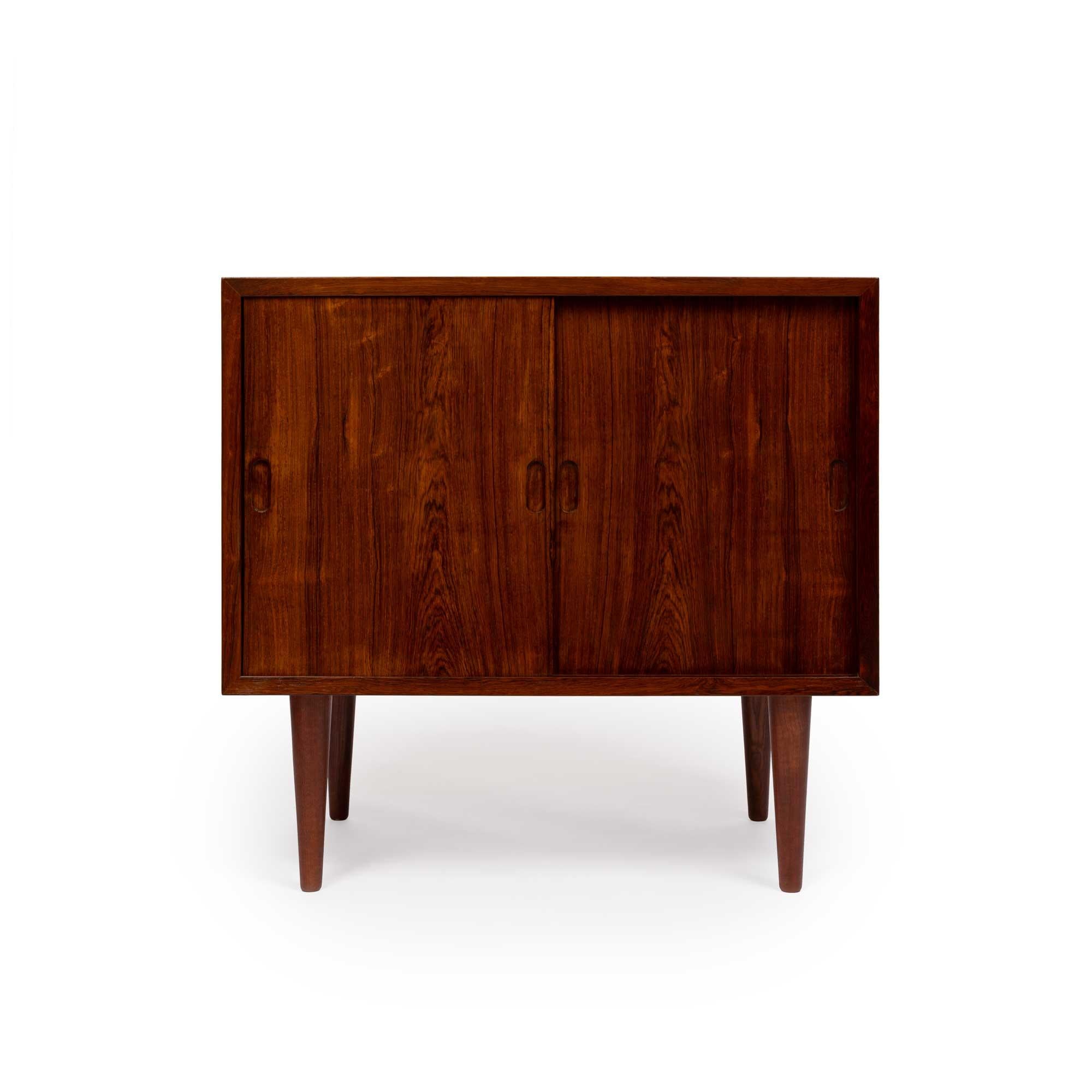 This vintage Danish Mid-Century chest is crafted from exquisite rosewood with stunning grain. It features two sides, each with three drawers and a shelf, offering ample storage. The two sliding doors, accented by carved solid wood pulls, glide