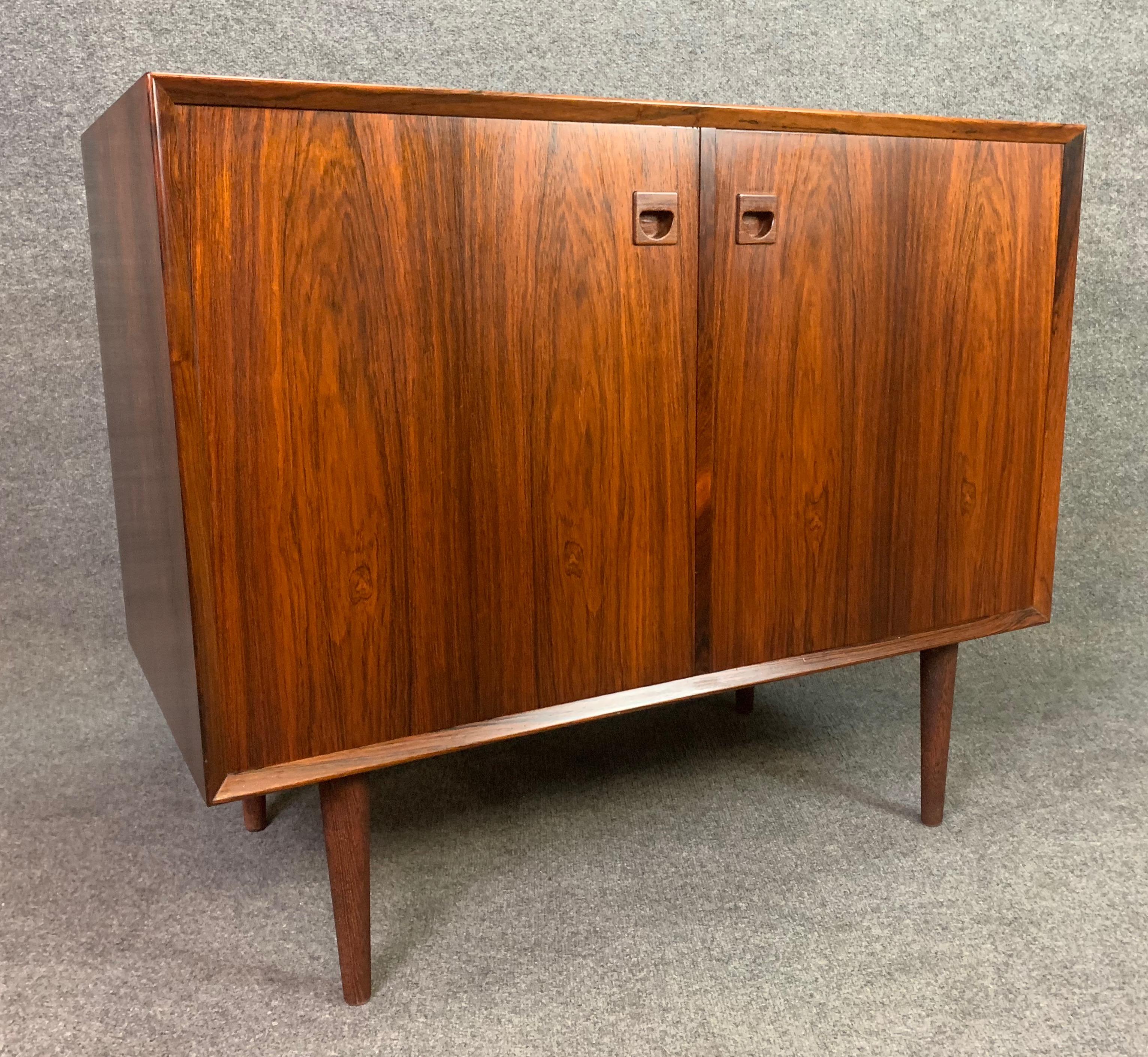 Here is a beautiful Scandinavian Modern case piece manufactured by Brouer Møbelfabrik in Denmark in the 1960s.
This lovely cabinet features a vibrant wood grain, sculpted recessed pulls, tapered legs and two large doors revealing a cupboard with an