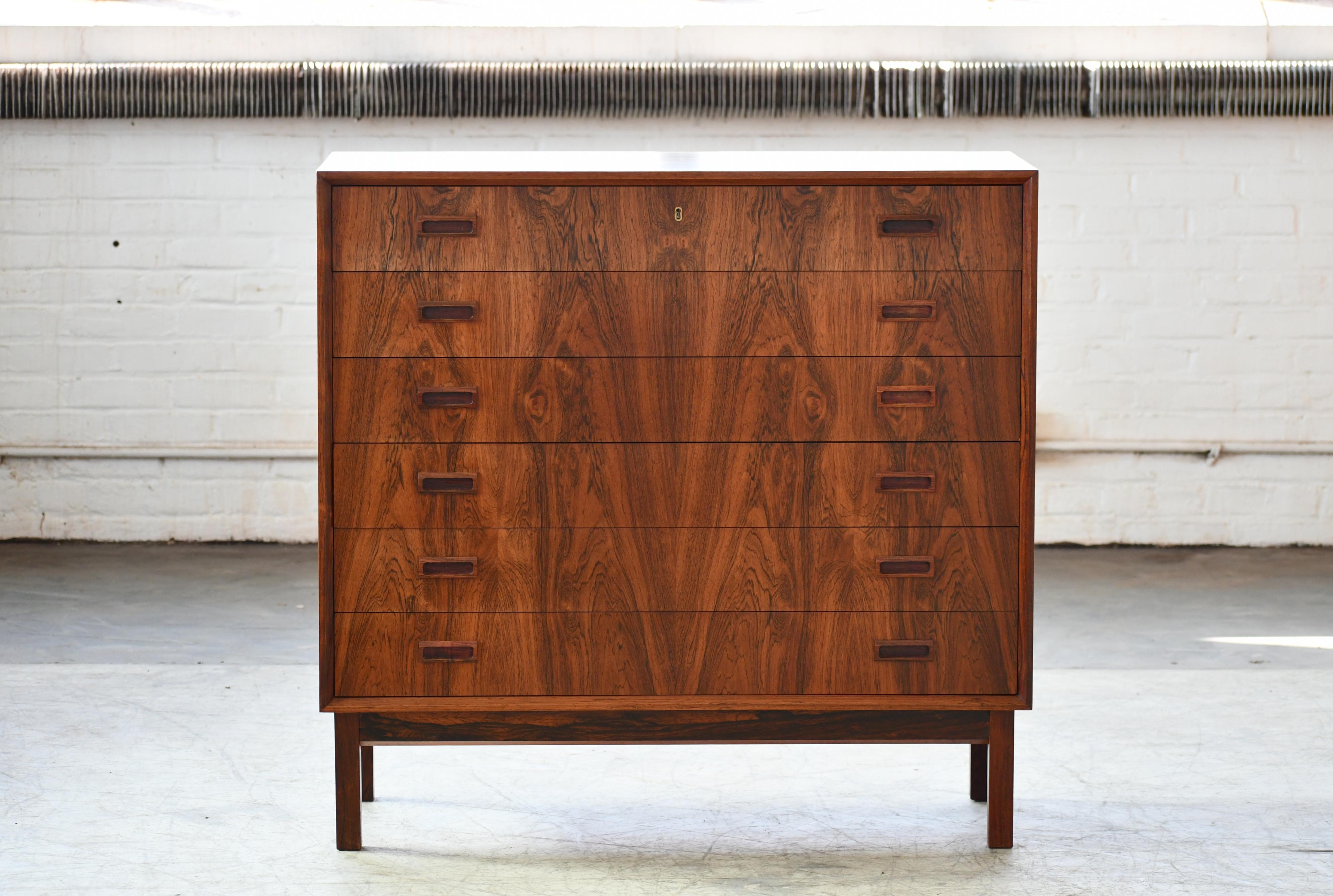 Exquisite 1960s rosewood chest of drawers with six large drawers in book matched rosewood veneer. Highest quality craftmanship with solid edges and carved drawer pulls. Beautiful deep color and grain. Raised on a base of solid rosewood. Designed by