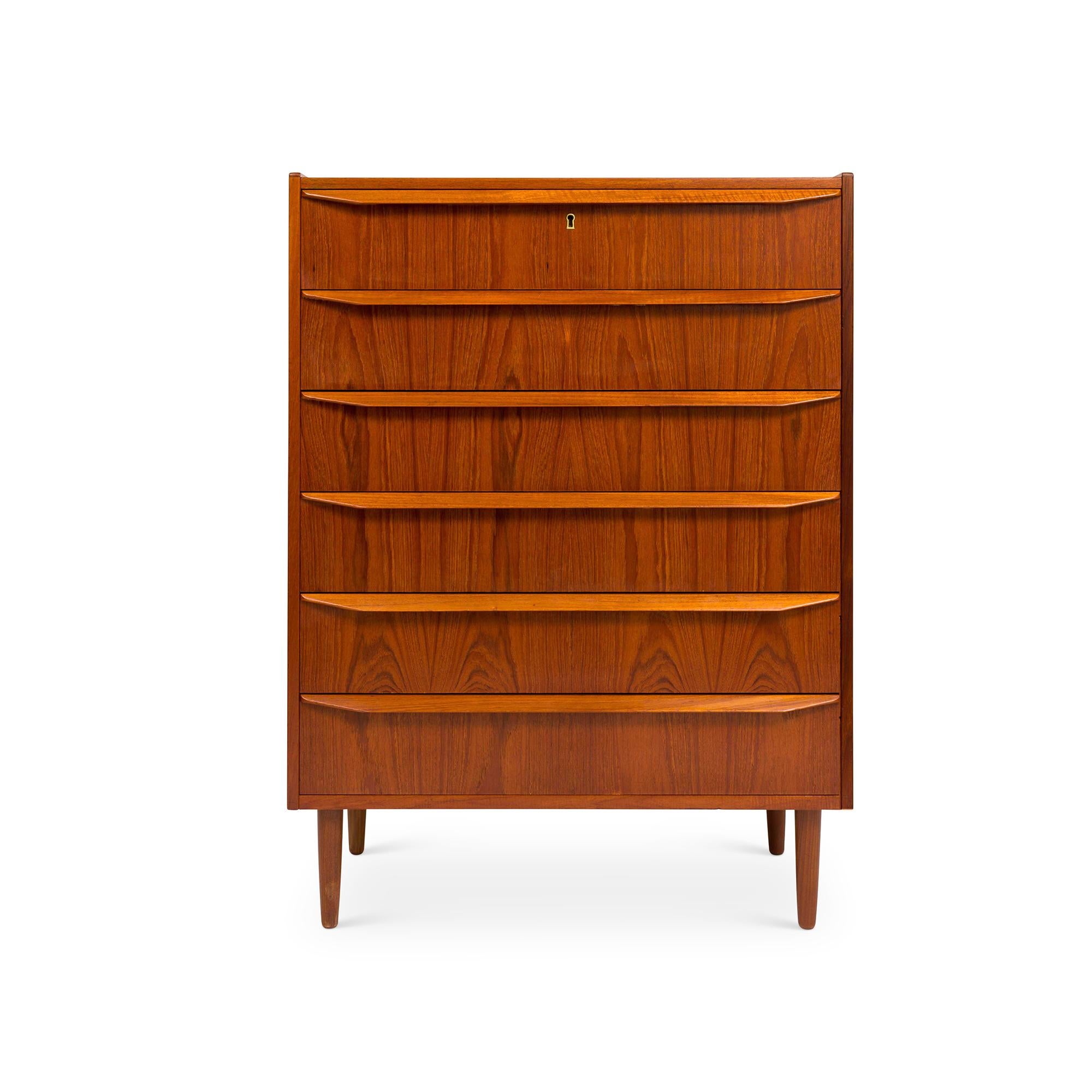 Una asombrosa cómoda danesa vintage de mediados de siglo de 1960, con seis cajones y fabricada en teca, es un emblema del diseño atemporal. La cómoda exhibe un fascinante veteado de teca, complementado con tiradores de cajón esculpidos alargados. Su
