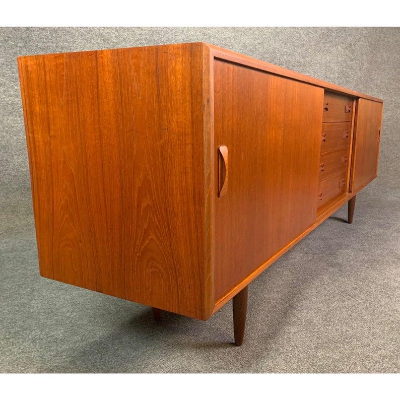 Here is a classic Scandinavian Modern credenza in teak wood manufactured by Clausen & Søn in Denmark in the 1960s.
This long sideboard, recently imported from Copenhagen to California, features a central bank of four drawers with bow tie shape