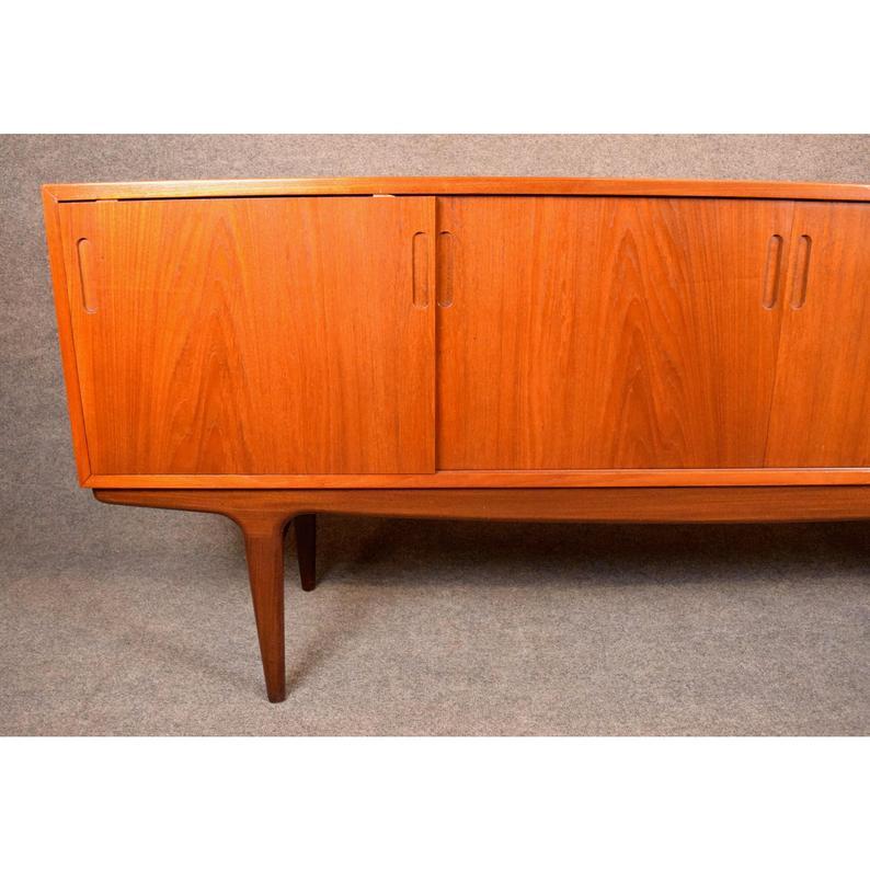 Here is a superb 1960s Scandinavian Modern sideboard in teak wood recently imported from Denmark to California before its restoration.
This large credenza has a vibrant wood grain, features a set of four sliding doors and seats on a sculptural and