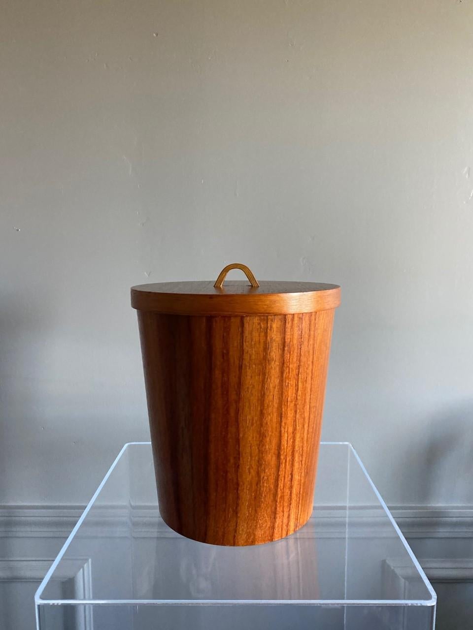 Unique and beautifully crafted Danish midcentury teak ice bucket. This piece has minimal, clean lines while enveloped in the grain of teak with the insert of aluminum. The piece comes with original set of ice tongs. Linear in shape but rich in style.