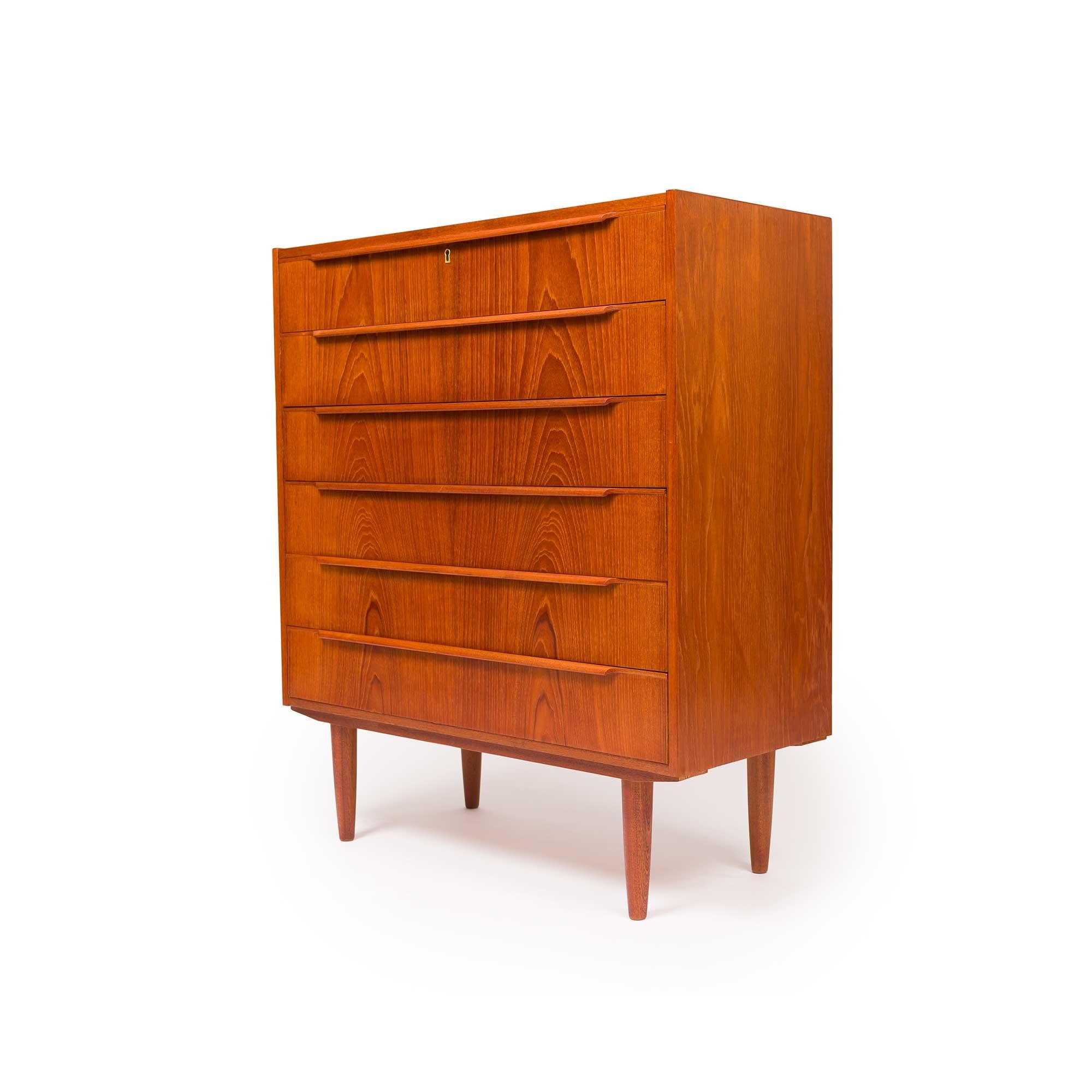 This mid-century modern Danish tallboy chest of drawers embodies the essence of Mid-Century design. Its six drawers, adorned with sculptured wooden handles and seamless dovetail joins, effortlessly combine functionality with elegance. The natural