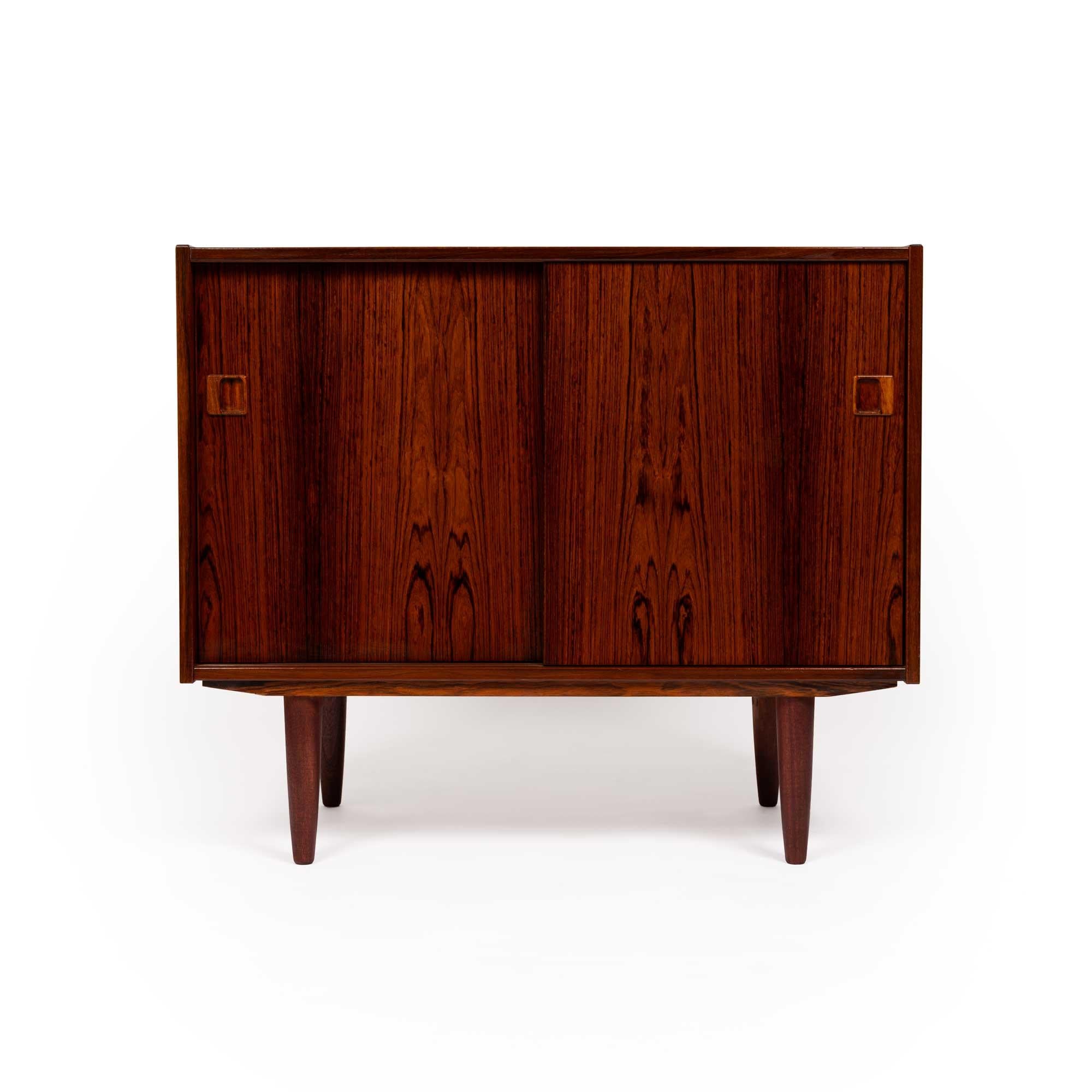 This stunning Danish Mid-Century credenza showcases the unparalleled beauty of richly grained rosewood, exuding timeless elegance. The rich dark wood grain flows seamlessly across the surface, a true testament to expert craftsmanship.

Designed with