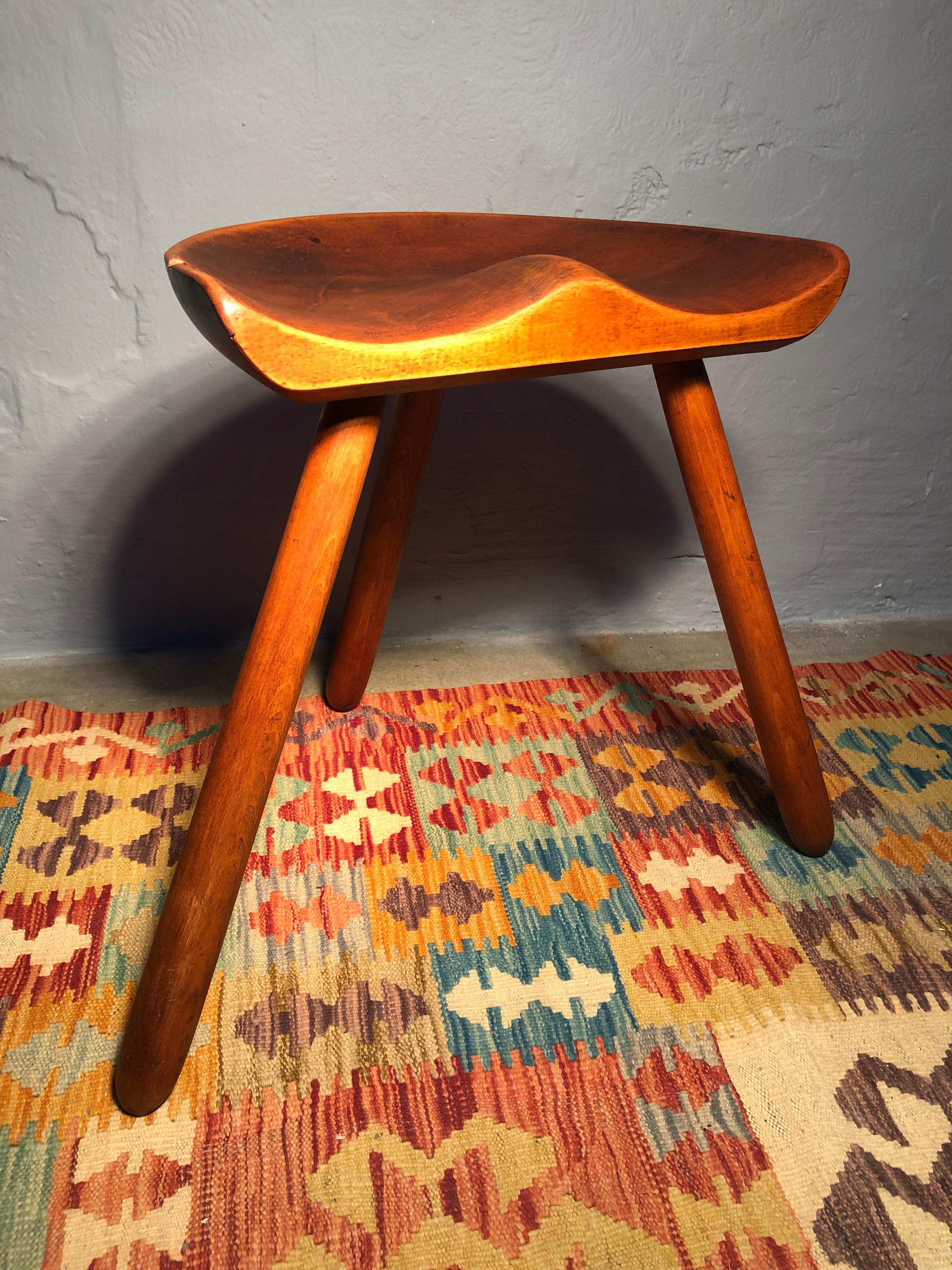 A mid Century milking Stool in beech wood. 
With a sculptural and simplistic Scandinavian design and with a carved seat and turned legs. 
The stool has been sanded and waxed. 
One small repair to the edge of the seat visible in the pictures. 
With