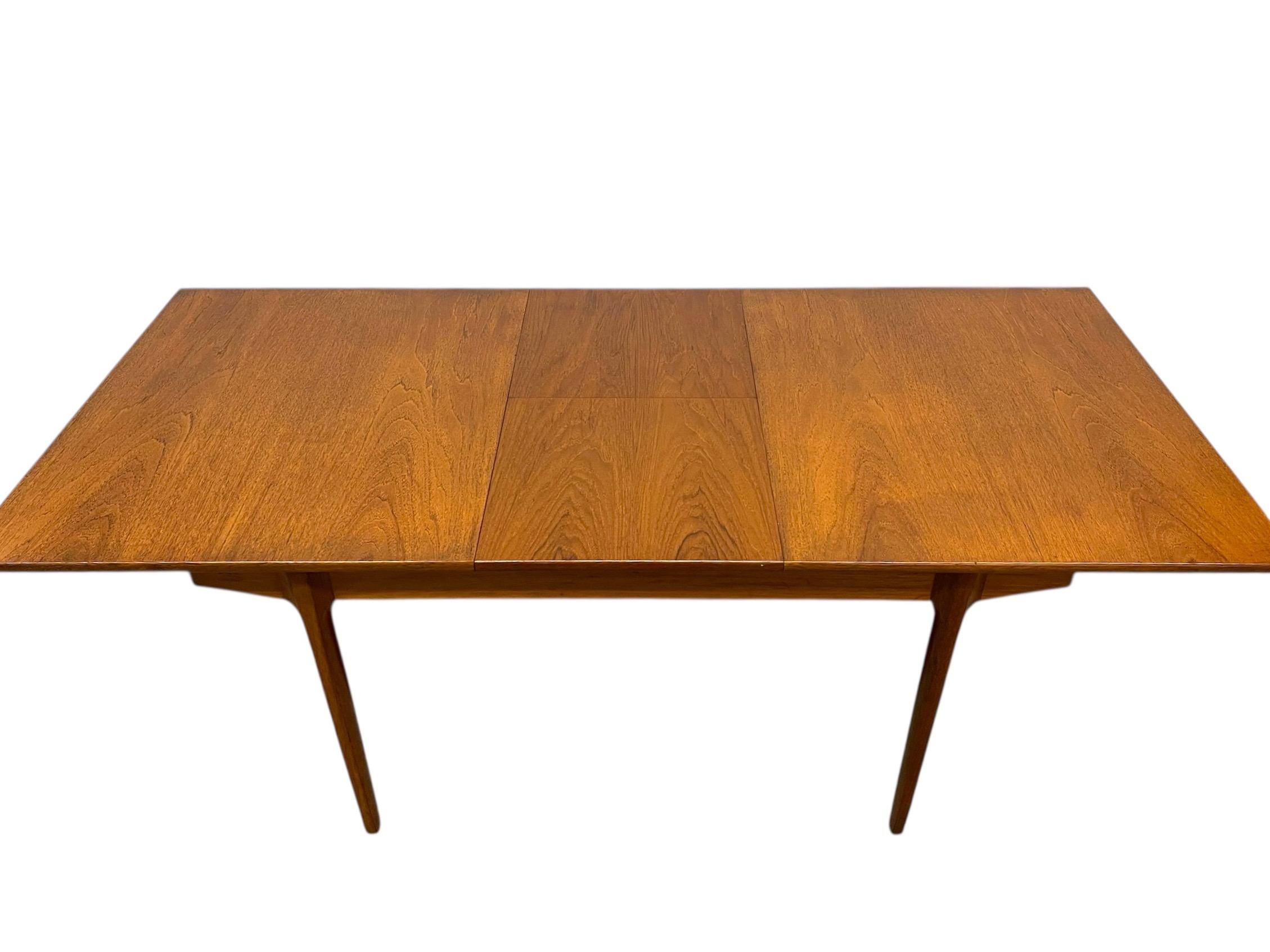 This vintage Danish Modern expanding dining table features a clean, minimalist silhouette and a warm finish characteristic of mid-century Scandinavian design. The tabletop displays a consistent and attractive wood grain,transitioning seamlessly
