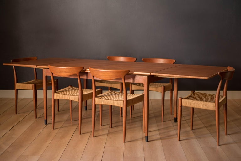 Mid century expandable teak dining table designed by Niels O. Moller for J.L. Mobelfabrik, Denmark. This versatile piece includes two draw leaf extensions that cleverly store underneath the table. Supported by tapered legs accented with black