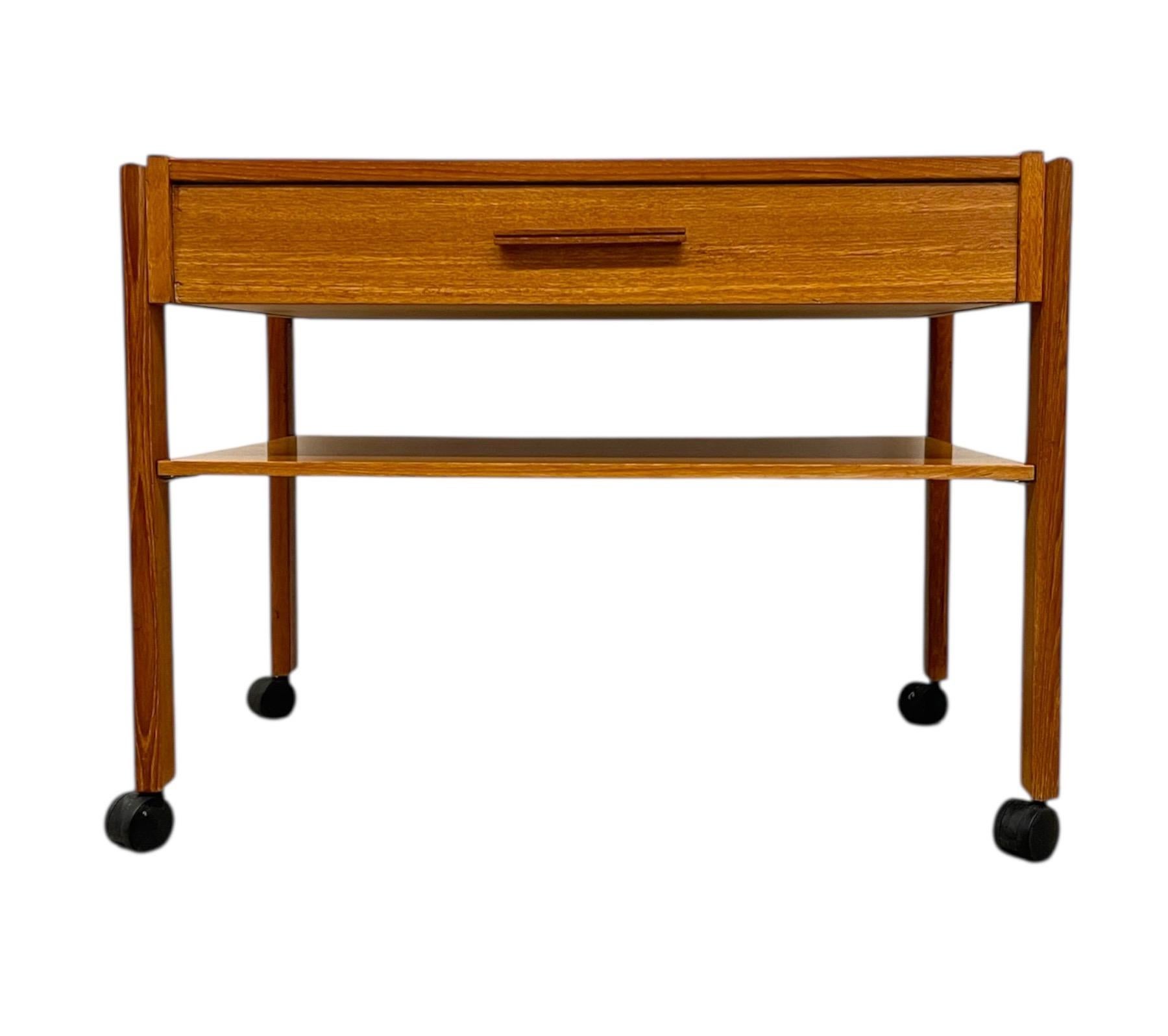 Elegant and functional, this vintage danish Modern rolling side table features clean lines and thoughtful craftsmanship typical of mid-20th-century Scandinavian design.Constructed in richly grained veneer, the table showcases minimalist styling with