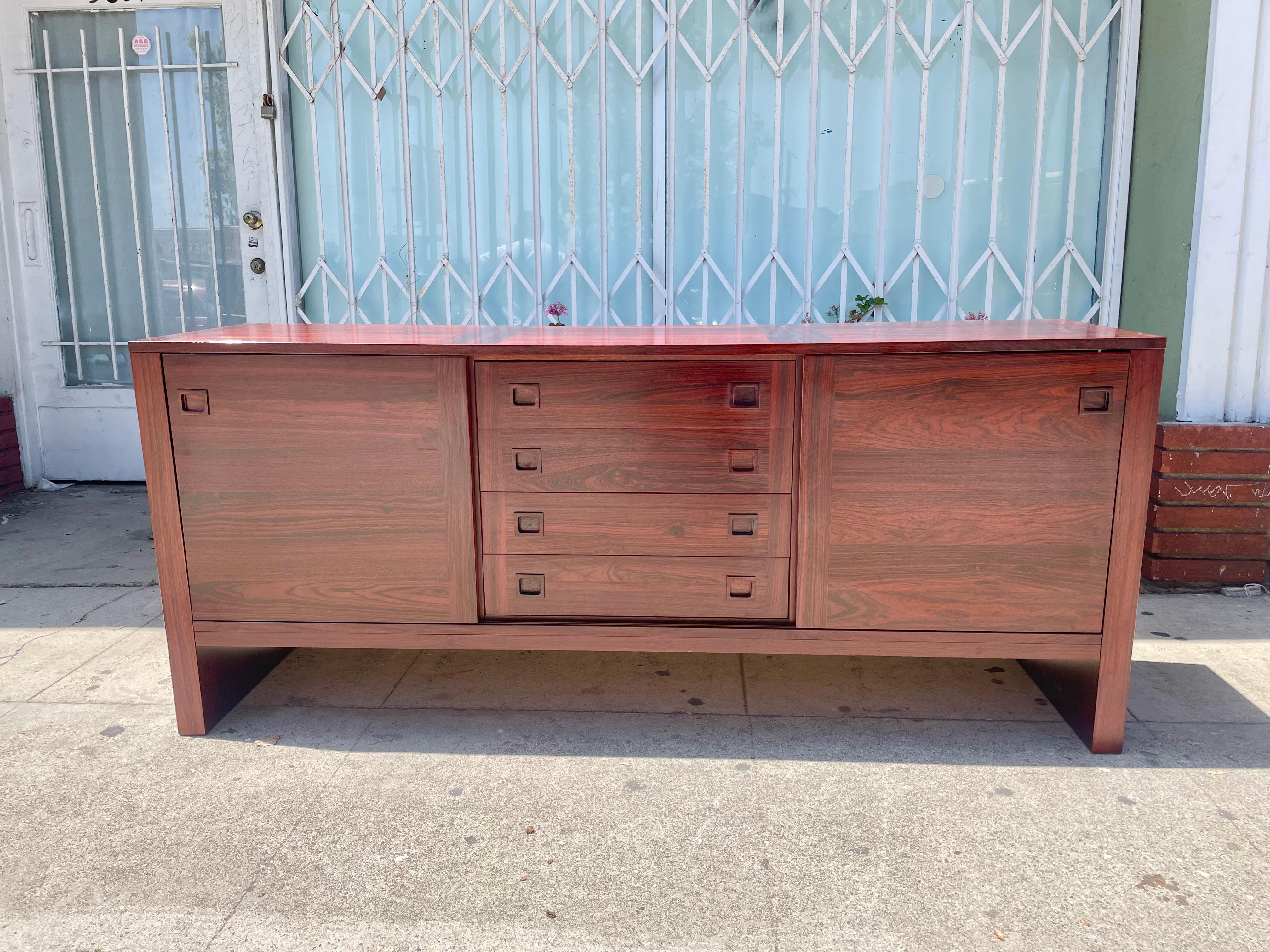 Danish modern Rosewood credenza this beautiful credenza can be used as a cabinet or dresser. It features a beautiful rosewood frame with four drawers in the middle and one shelf on each side covered with slide doors, making it easy to move it from