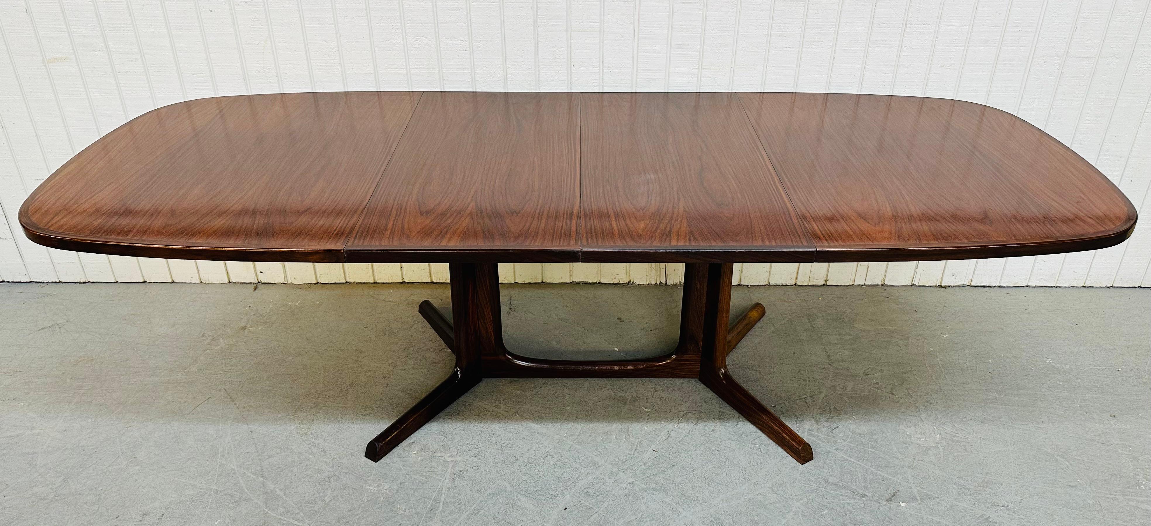 This listing is for a vintage Danish Modern Rosewood Dining Table. Featuring a slightly rounded banded rosewood top that extends up to 102” L with both 19” leafs inserted, a rosewood double pedestal style center table base, and a beautiful rosewood