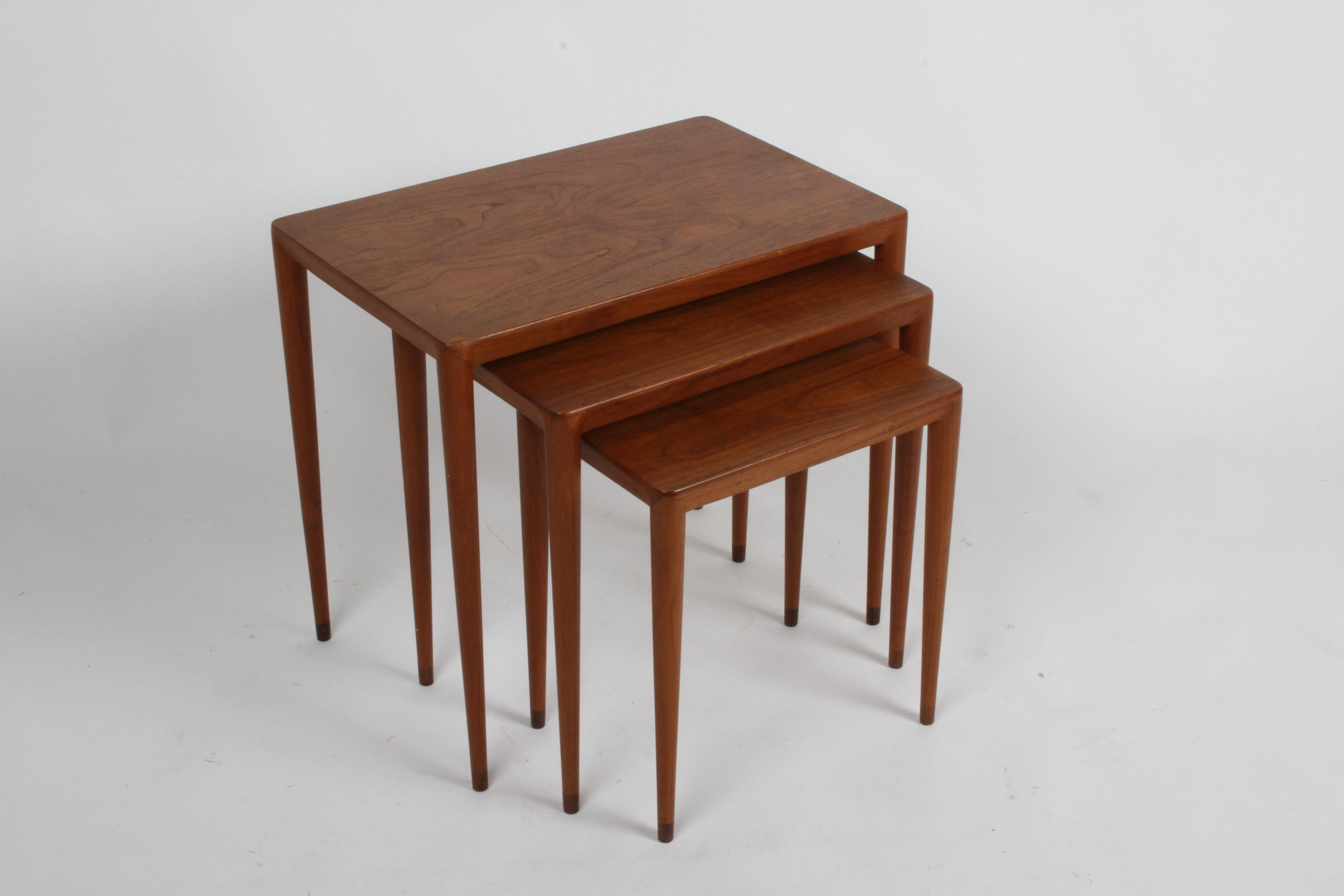 Beautiful set of three teak vintage Danish modern nesting tables with rosewood tips to the tapered legs. Original owner purchased them in the 1960s at the retailer Illums Bolighus in Copenhagen, Denmark. Retains brass label Illums Bolighus