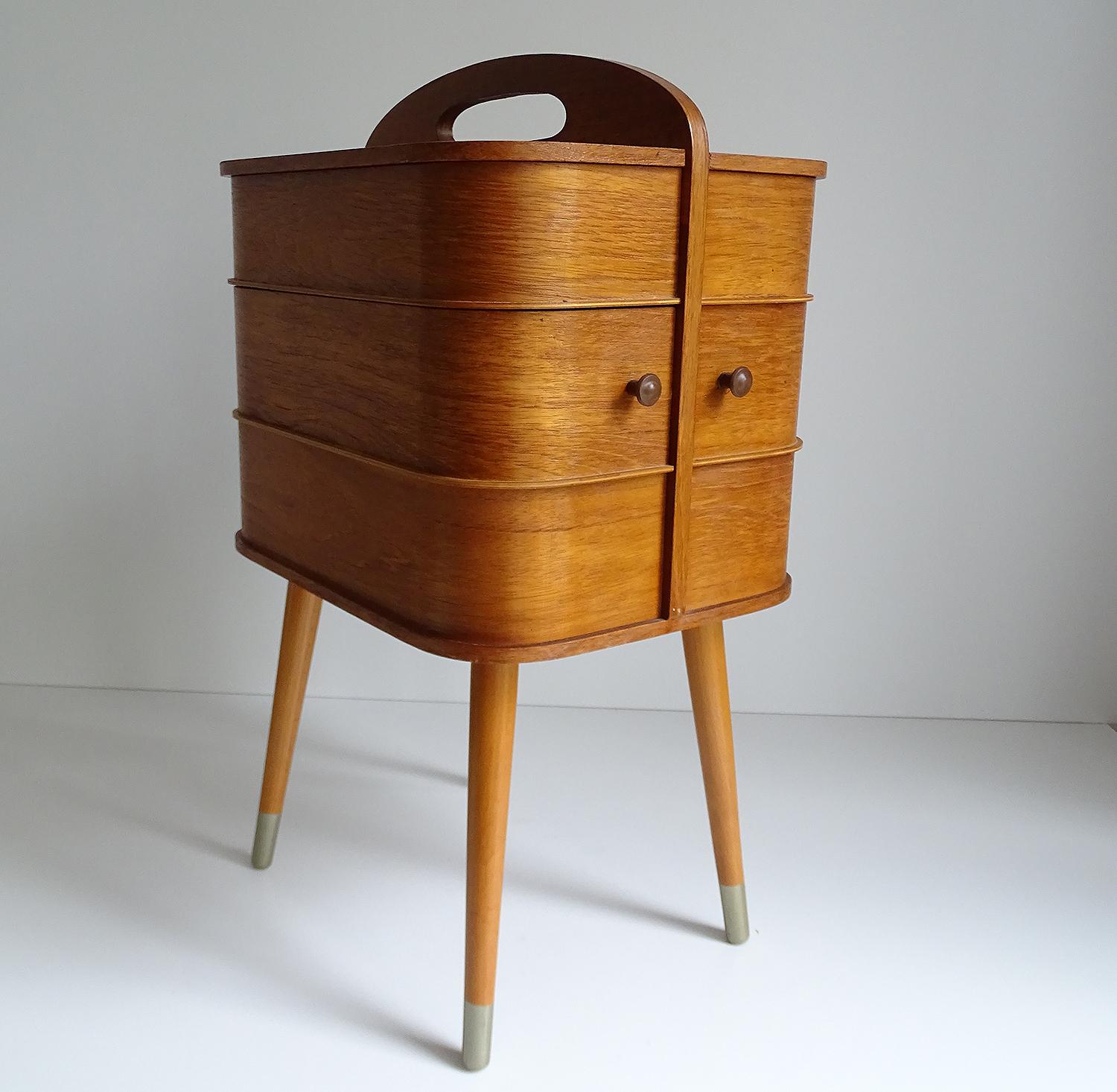 Stunning original Danish modern midcentury 1950s-1960s sewing box / side table with handle on top.
The box features 2 drawers which rotate sidewise revealing underneath 2 more compartments, the uppermost levels have also compartments under side