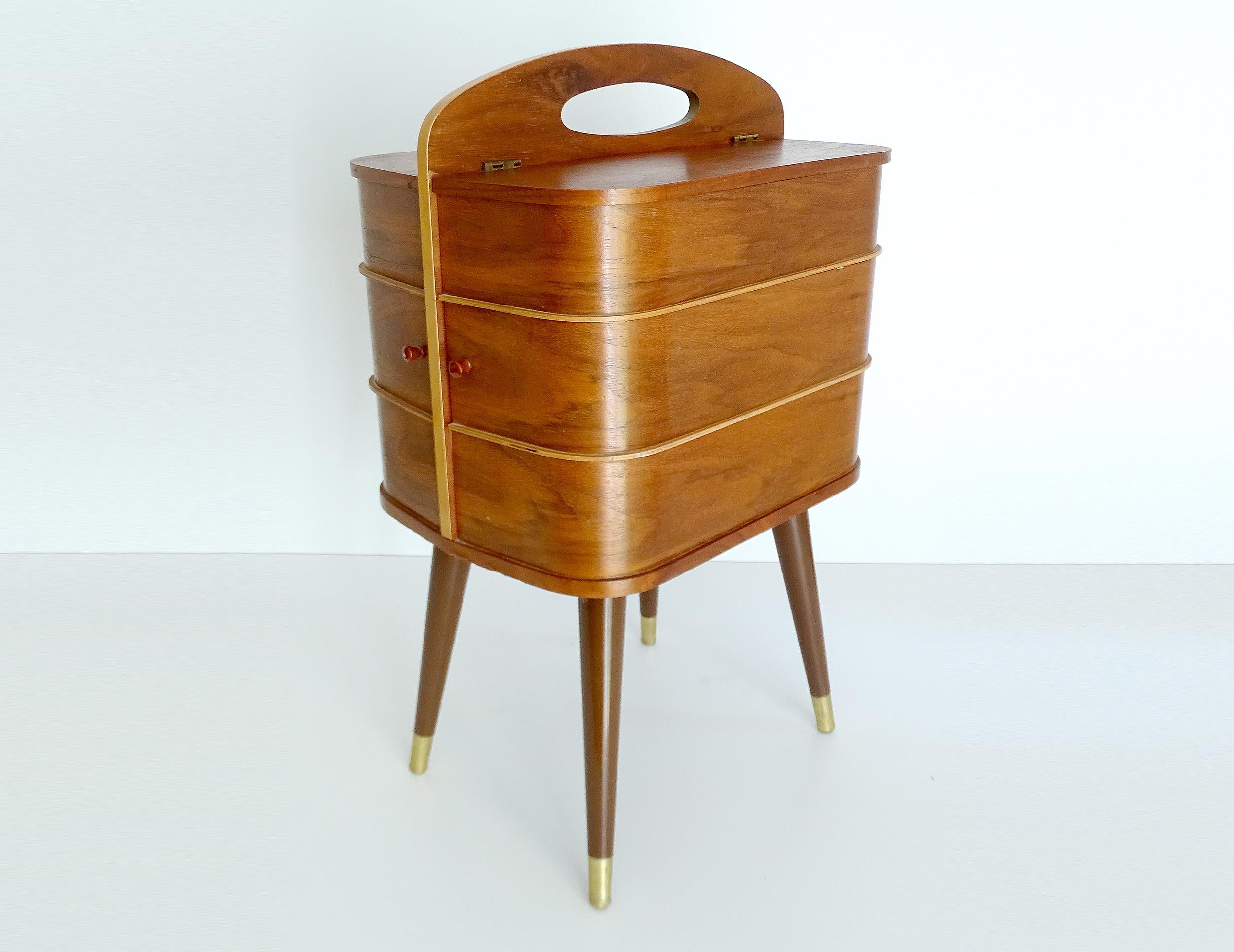 Stunning original Danish modern midcentury 1950s-1960s sewing box or side table with handle on top.
The box features 2 drawers which rotate sidewise revealing underneath 2 more compartments, the uppermost levels have also compartments under side
