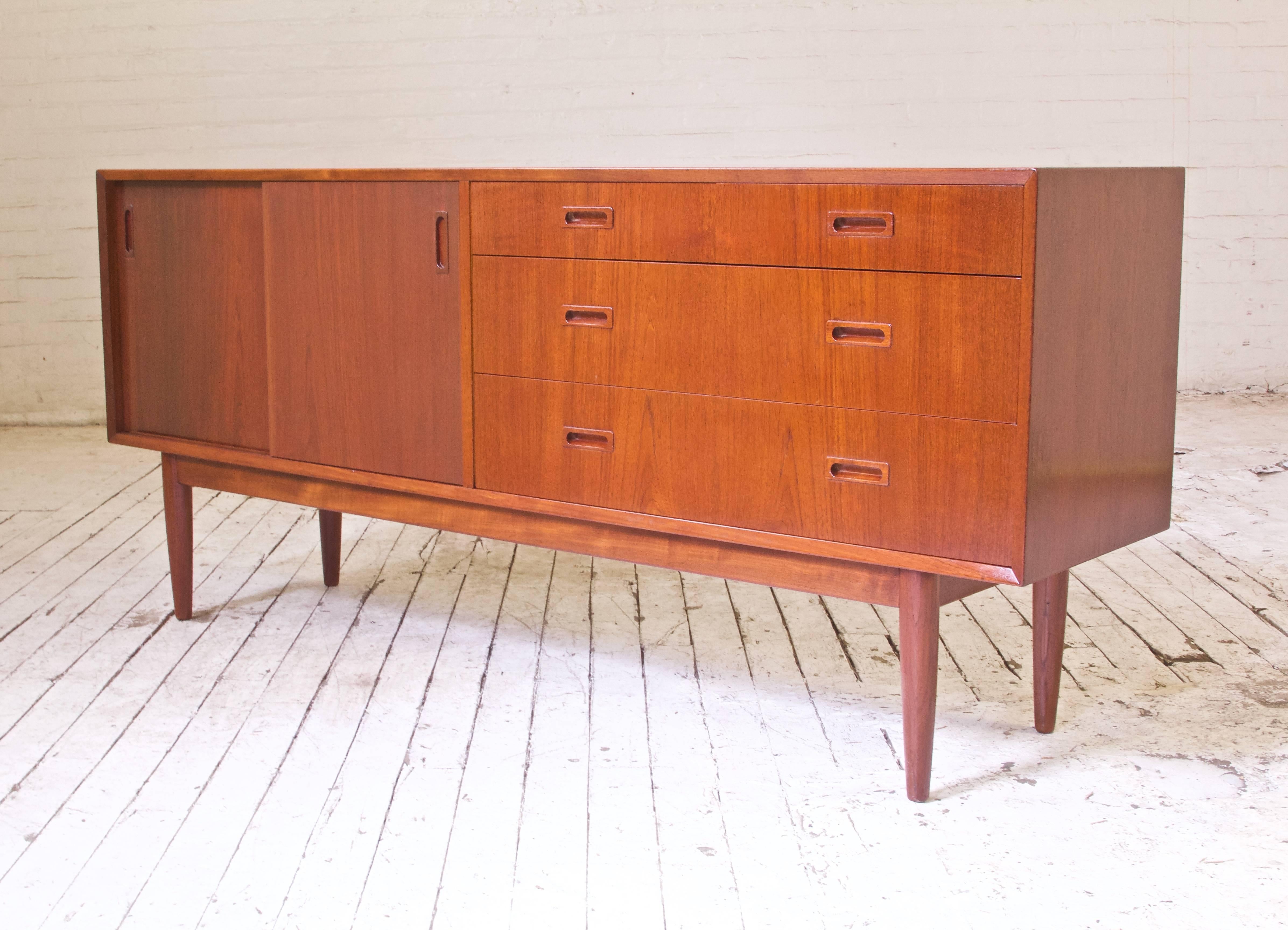 Lovingly restored and polished vintage Danish sideboard in teak with four drawers and two sliding doors. Sliding doors open to reveal two compartments complete with three adjustable shelves. Gorgeous tone throughout, the back of the piece is