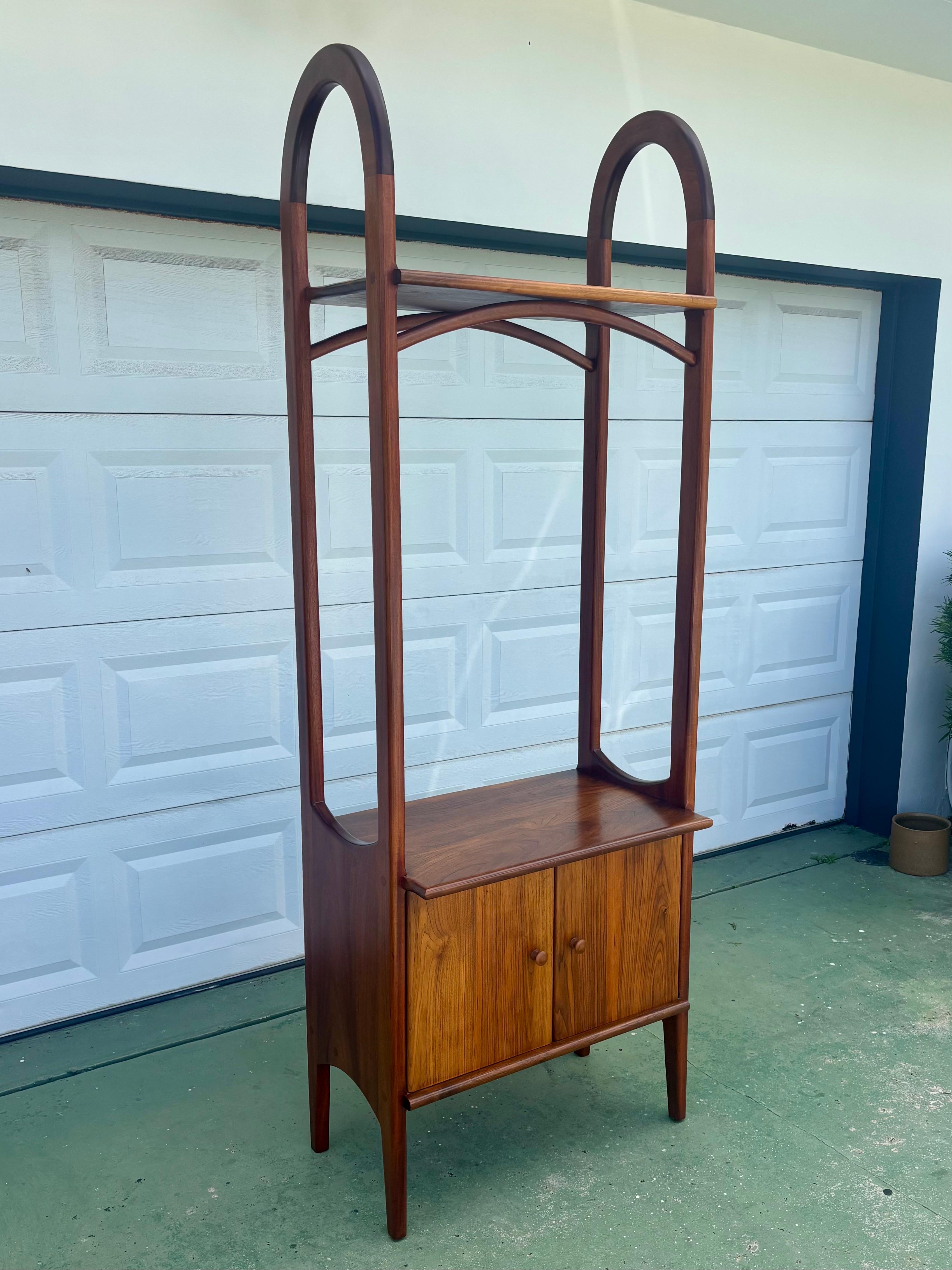 Elevating the language of Danish modern design, this architectural solid-walnut display cabinet is a commanding, gallery-worthy form—standing an impressive 89 inches tall with elegantly arched side frames that read like mid-century cathedral lines.