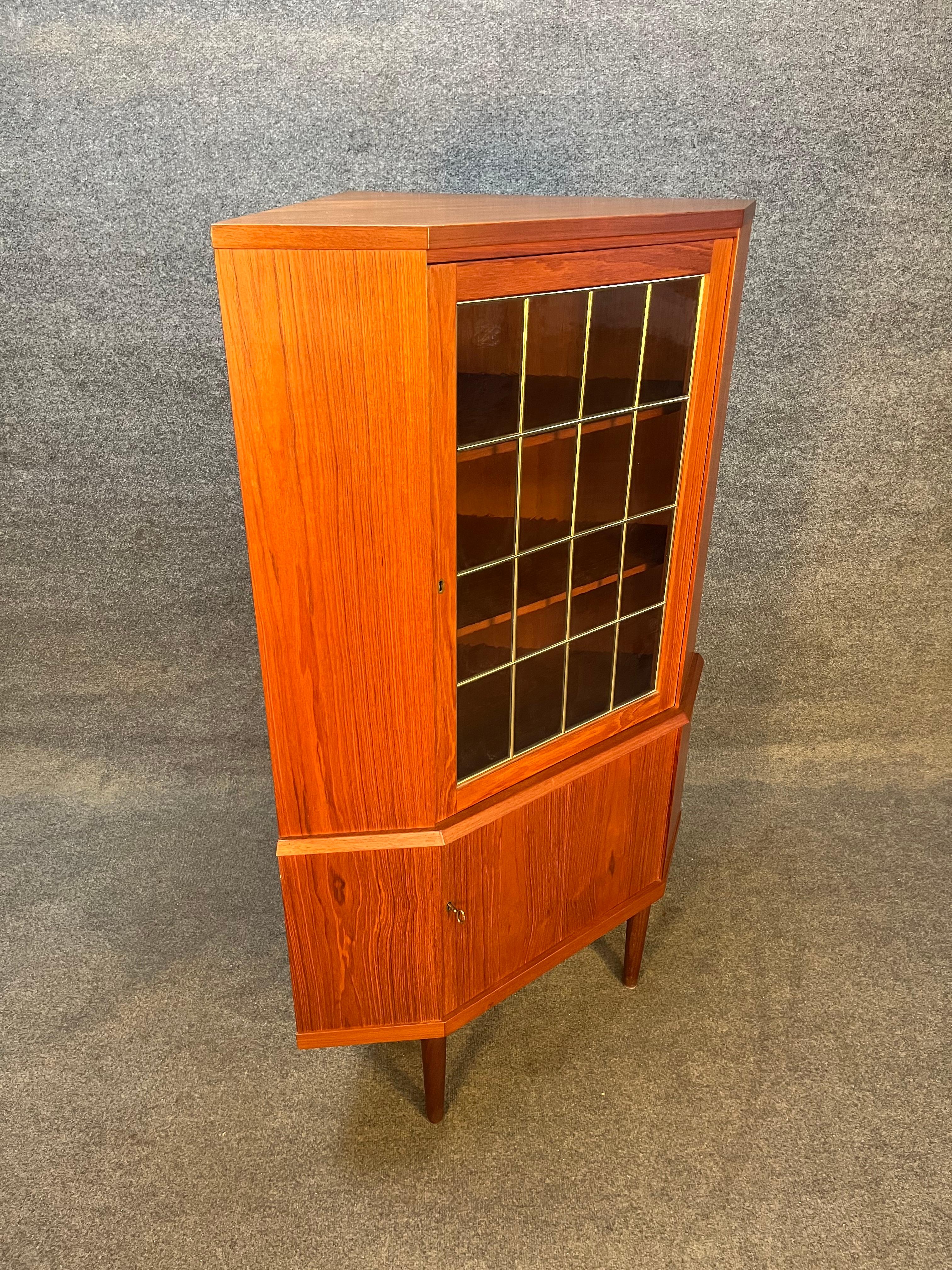 This Danish modern Mid-Century corner cabinet is perfect for any space with limited storage providing a ready to use dry bar or concealed storage. This piece features two locking cabinets that reveal storage with shelves, comes with original key. In