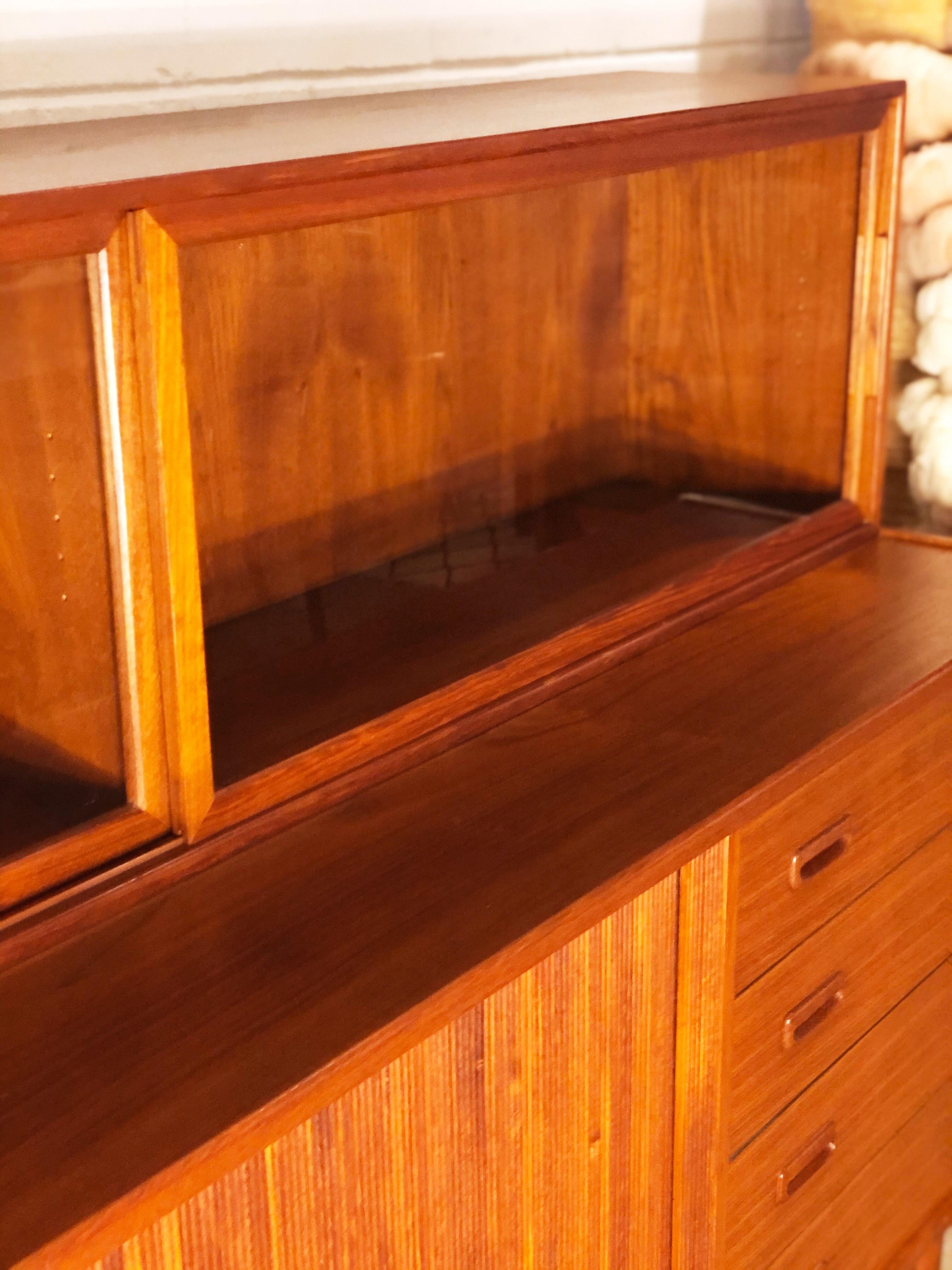 This vintage Danish modern teak credenza with removable upper display wood framed glass cabinet designed by Peter Hvidt is in overall excellent condition. This credenza features thick tambour doors, with interior shelving and drawers with sculpted
